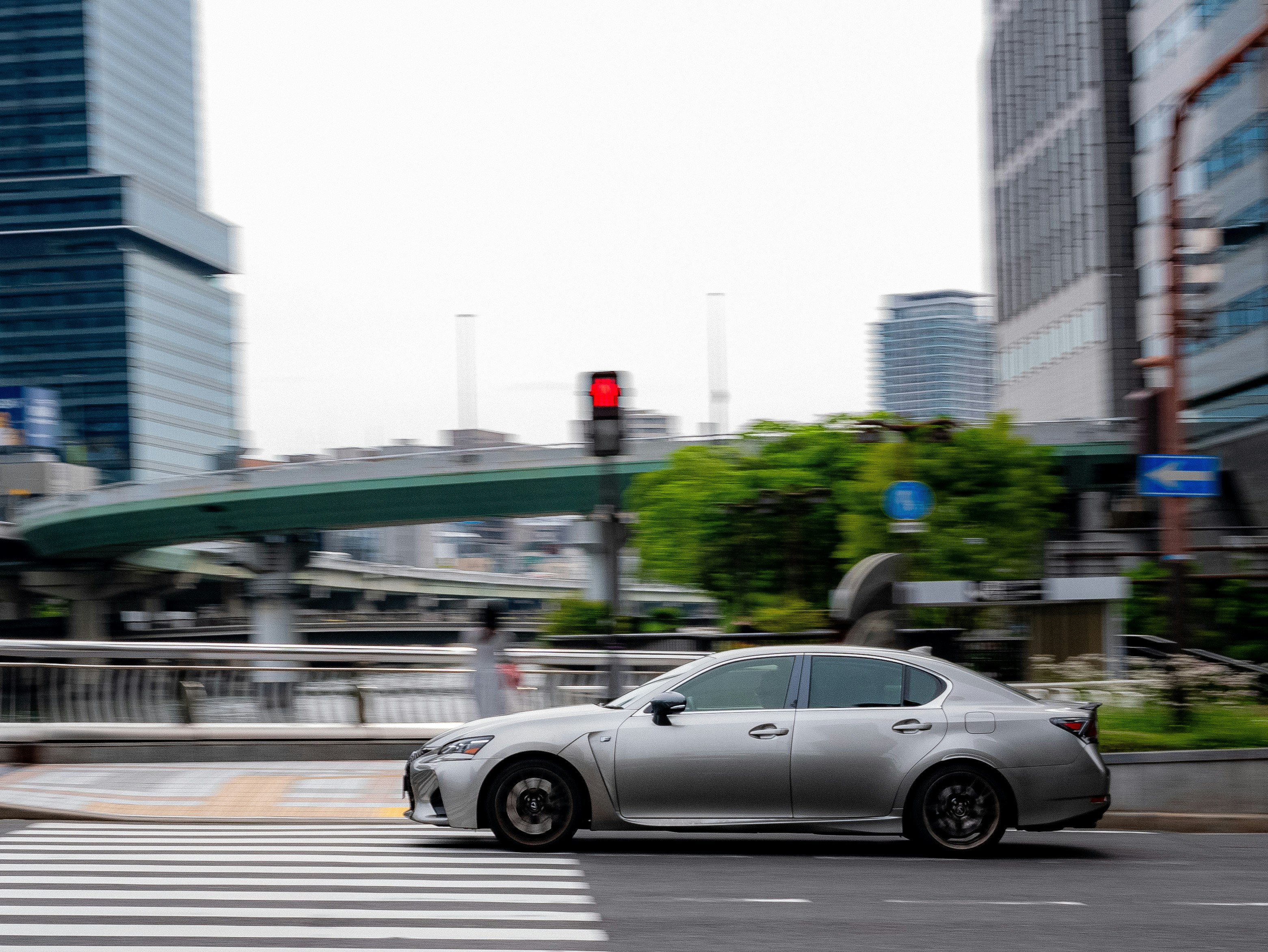 高層ビル街を走る白いスポーツカーのある交差点