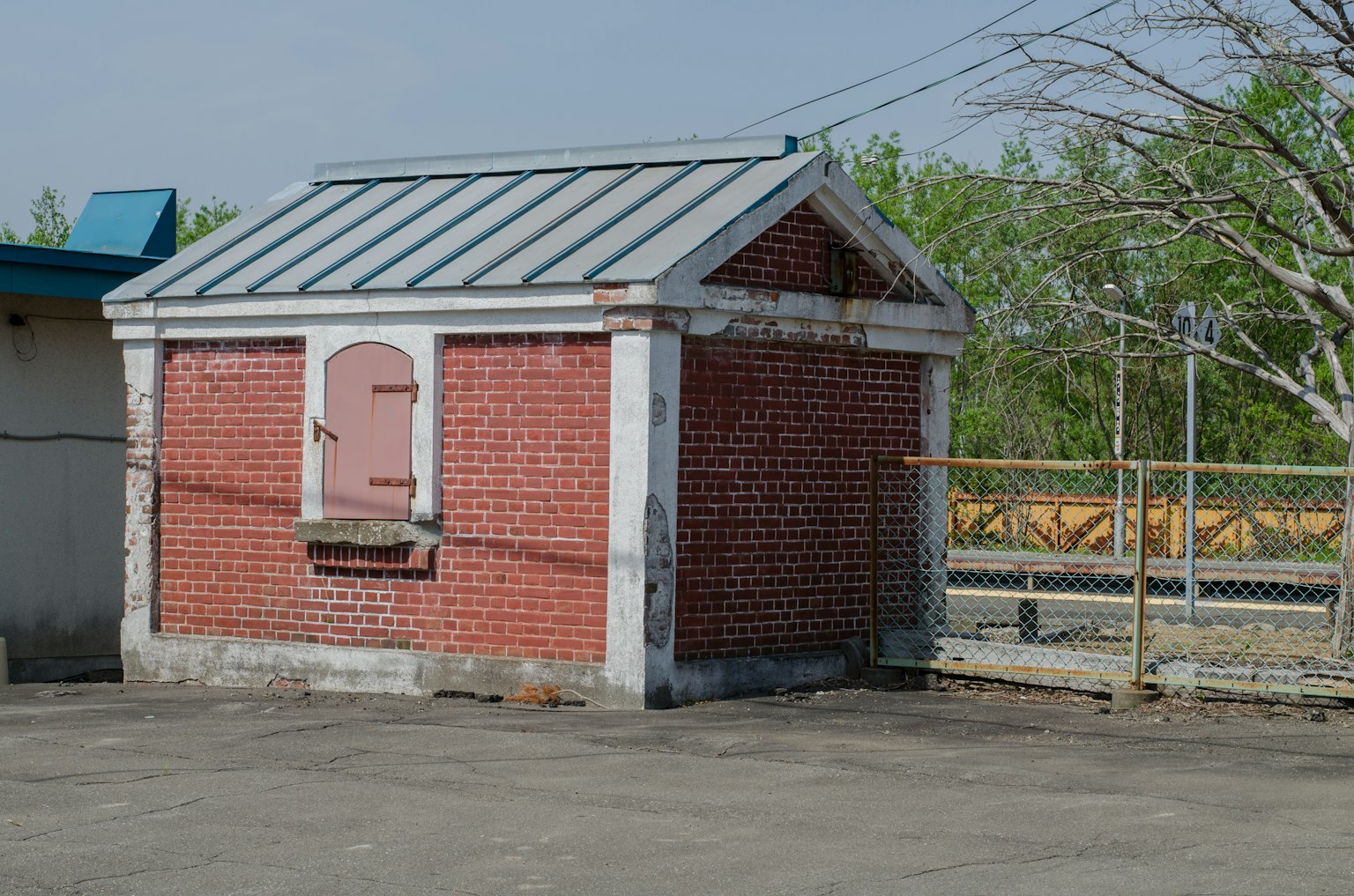 Un piccolo edificio in mattoni con un tetto in metallo e una porta rosa