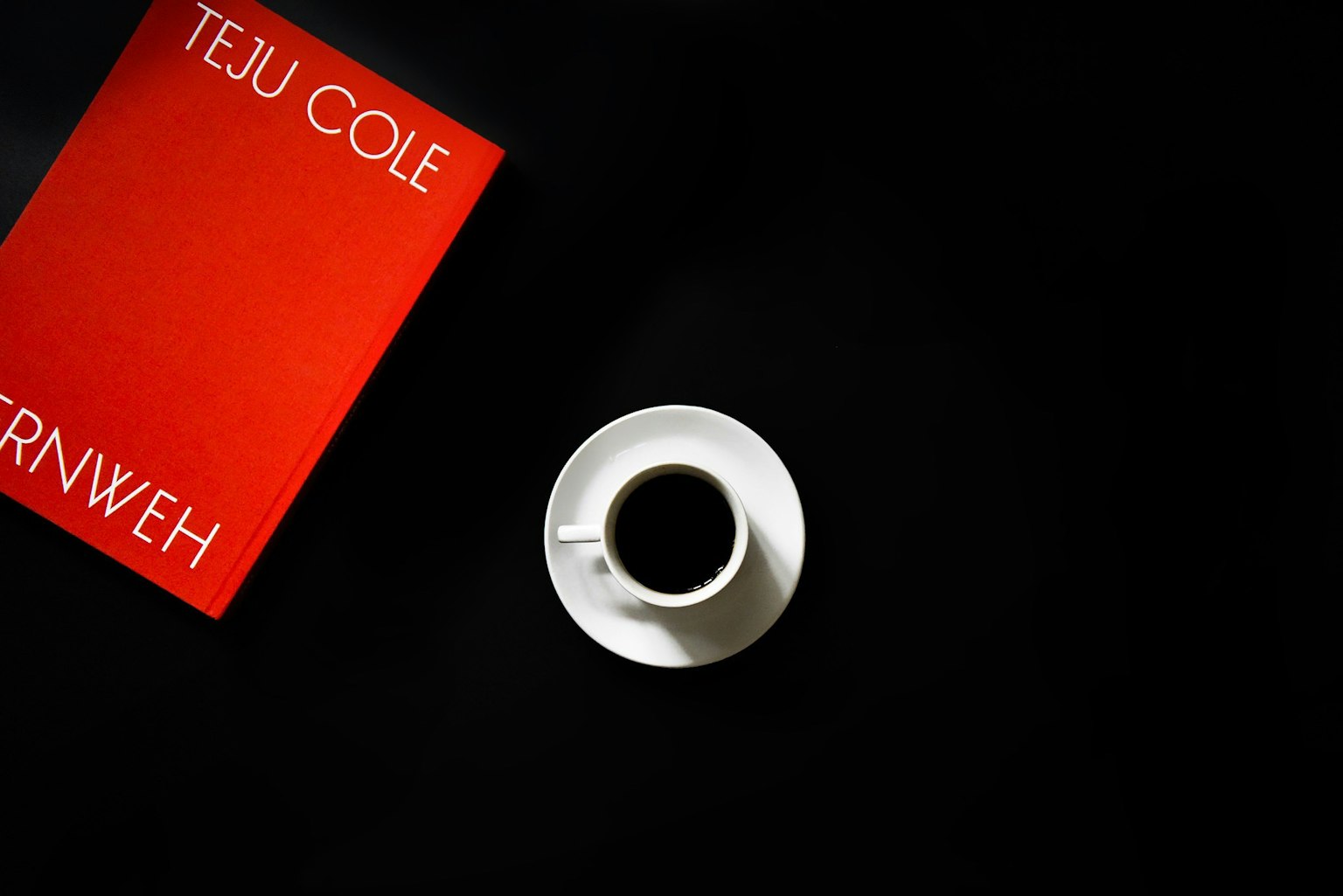 Red book cover with the title by Teju Cole and a white coffee cup on a black background