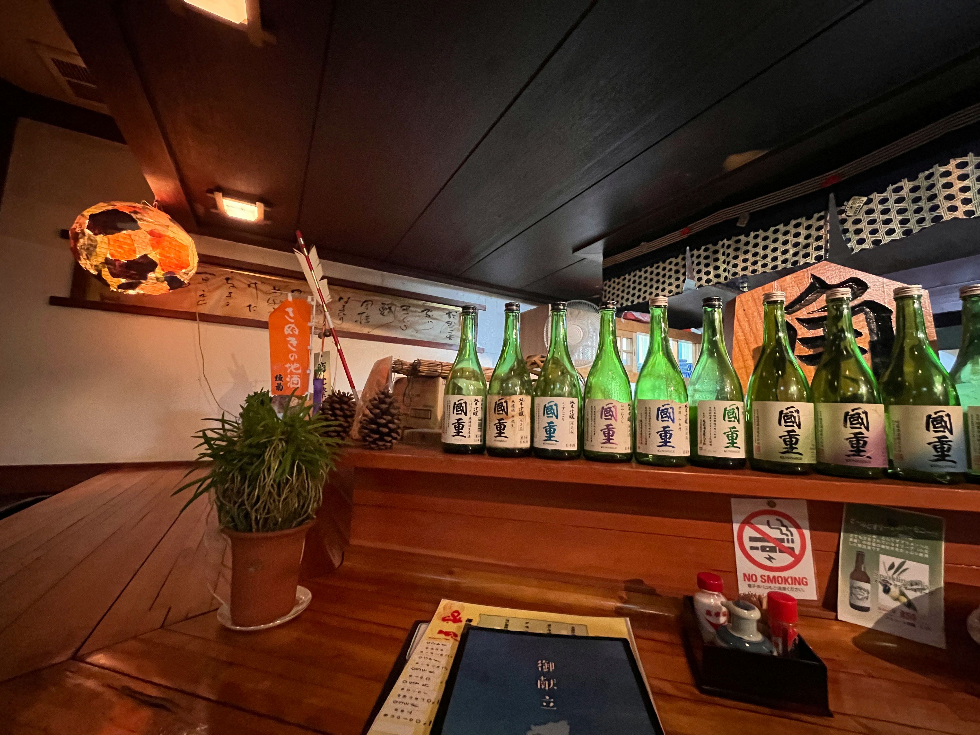 木のカウンターと酒瓶が並ぶ店内の棚