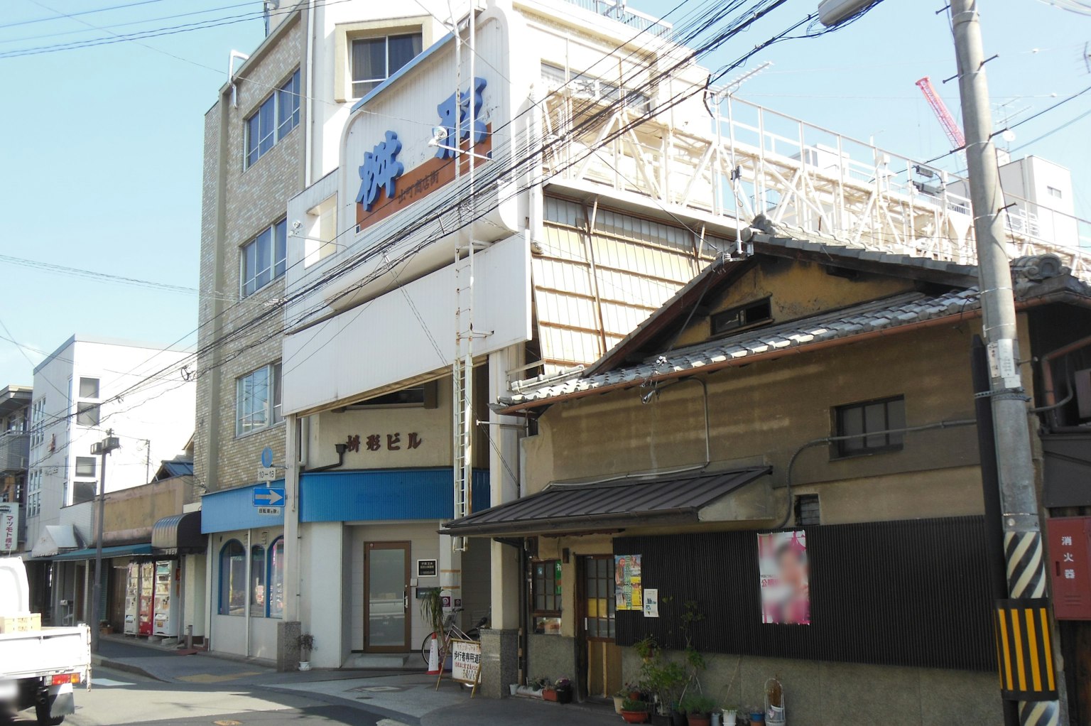 Un bâtiment moderne avec un panneau bleu à côté d'une maison japonaise traditionnelle dans une rue de la ville
