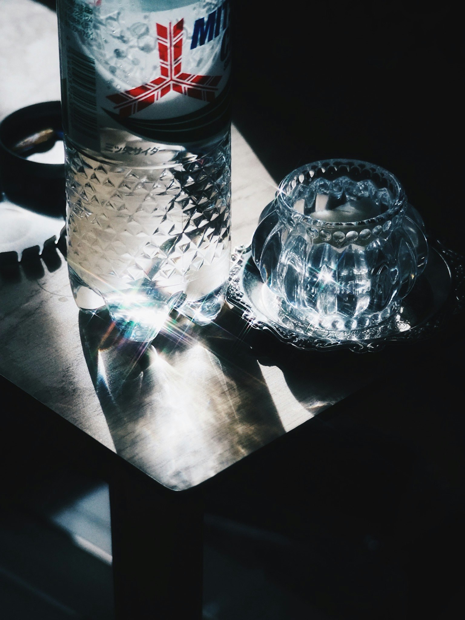 Una bottiglia d'acqua e un piatto di cristallo su un tavolo che riflette la luce