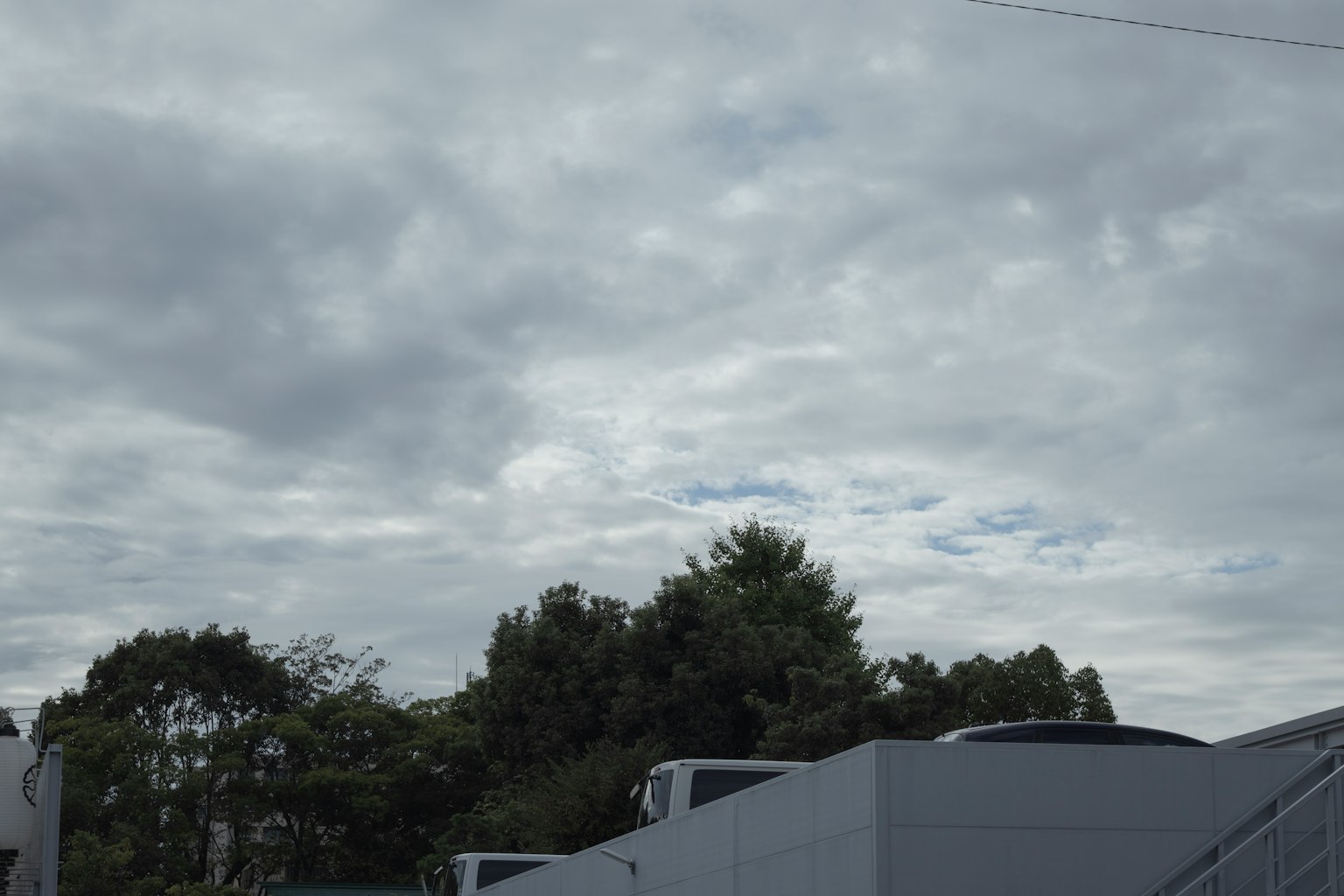 Cloudy sky with green trees in the background
