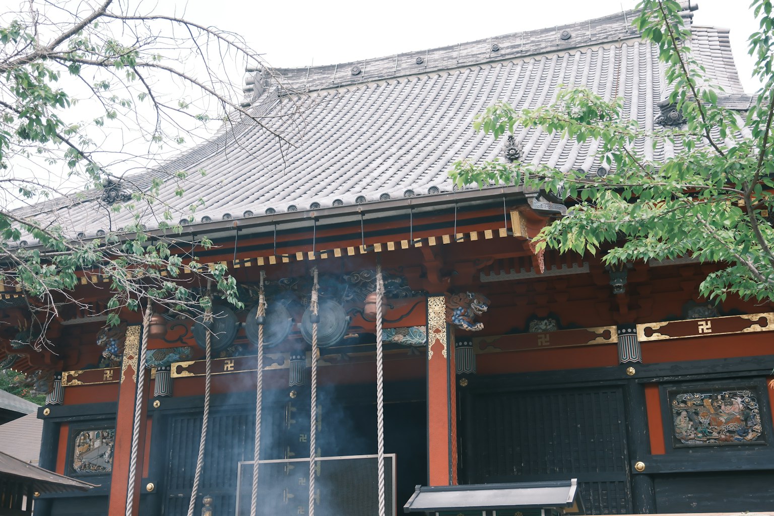 Exterior of an old Japanese temple with rising smoke decorative carvings on the walls traditional roof