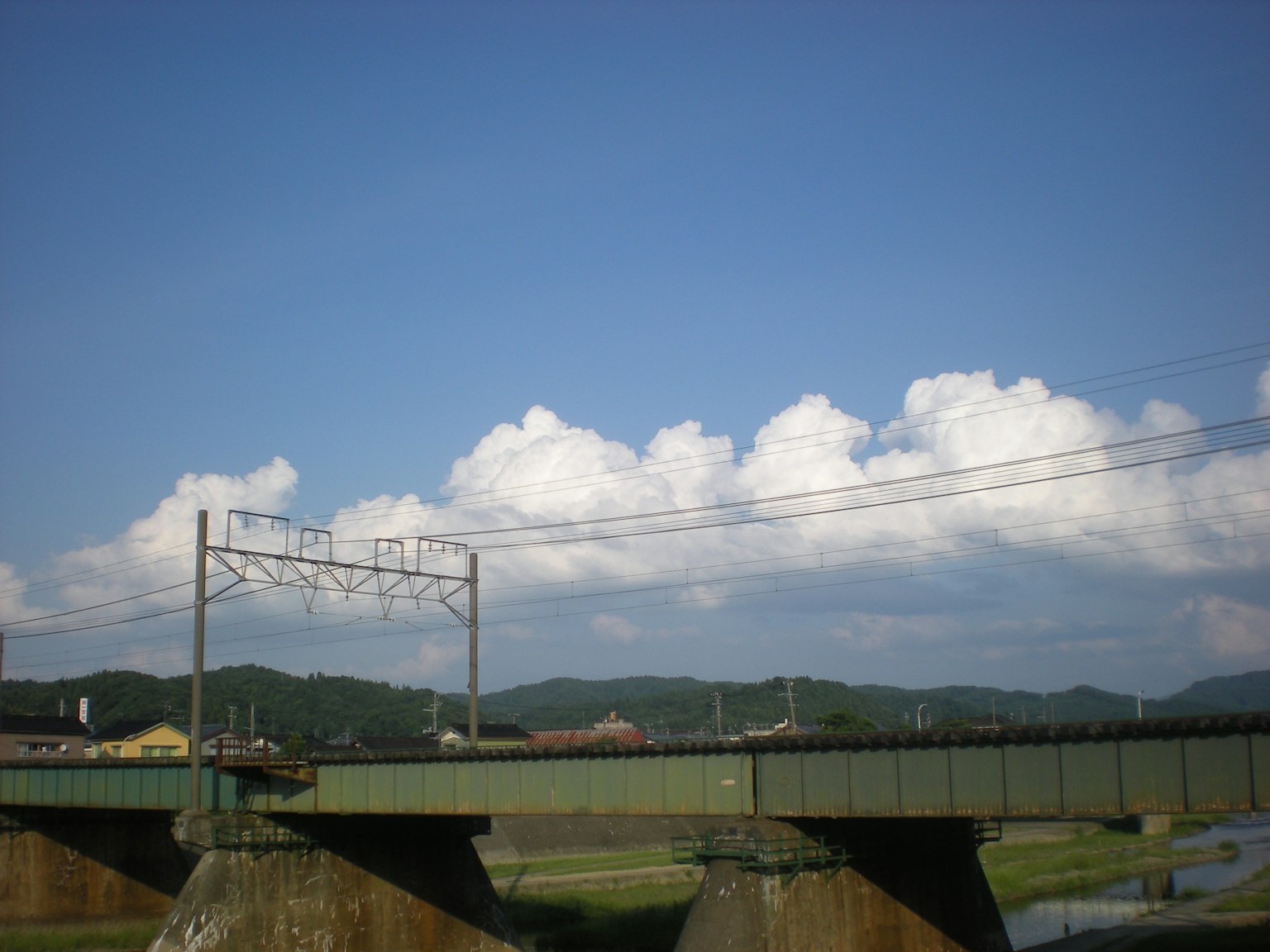 Pont vert sous un ciel bleu avec des nuages blancs duveteux