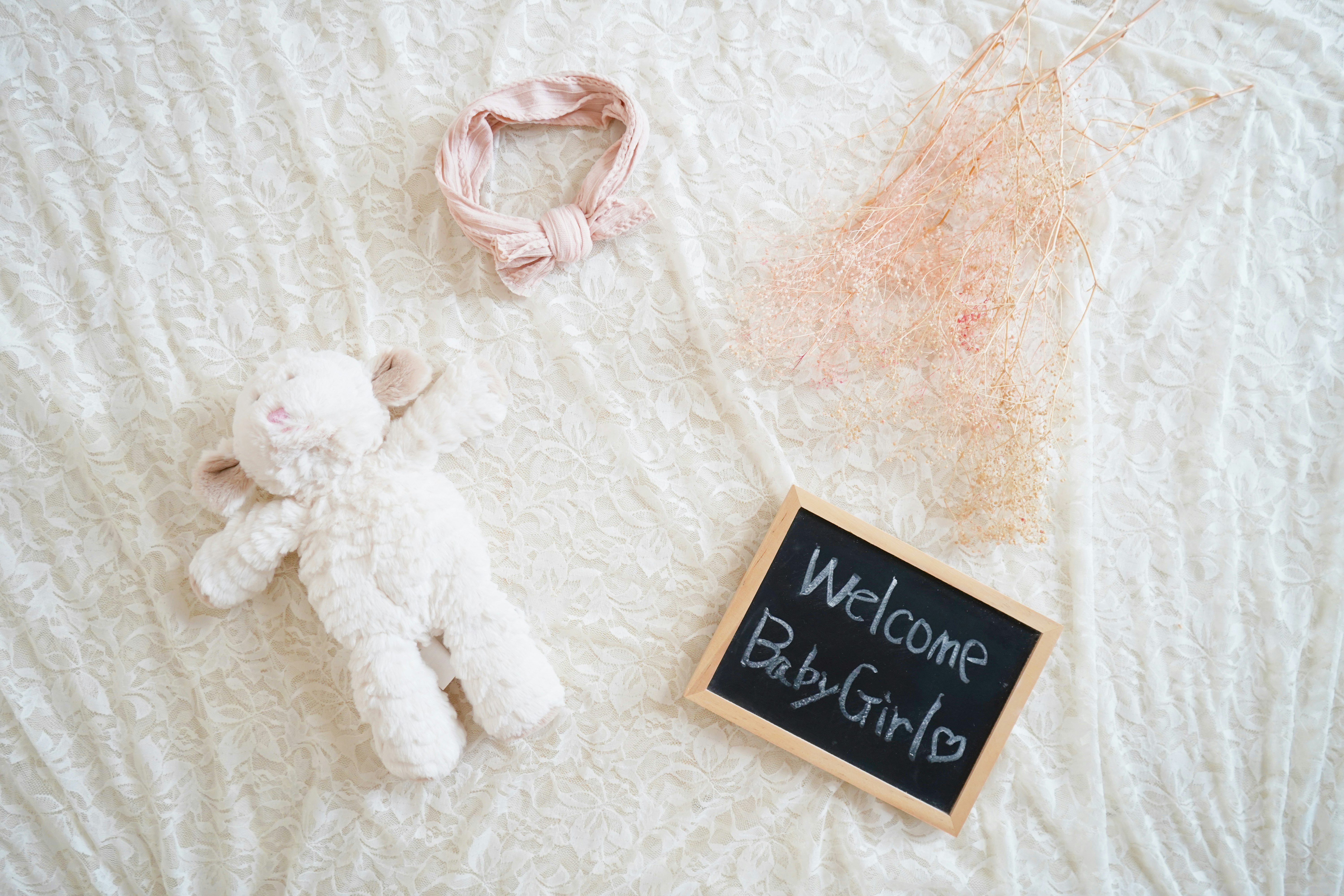ぬいぐるみと「Welcome Baby Girl」サインのあるベビーギフト