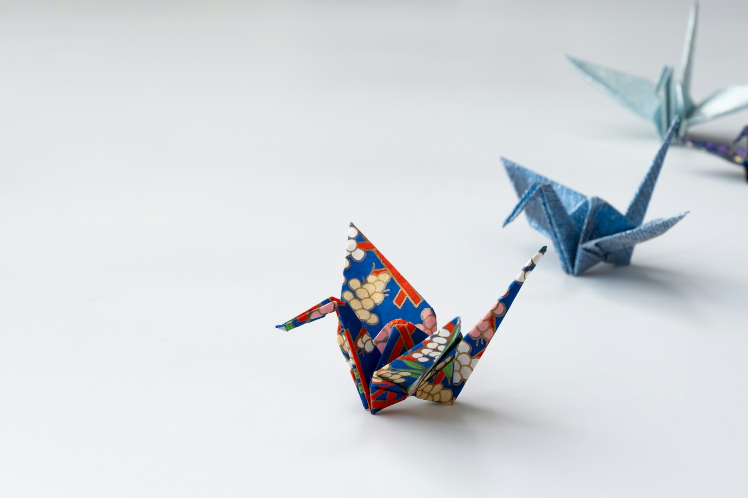 Grullas de origami coloridas dispuestas sobre un fondo sencillo