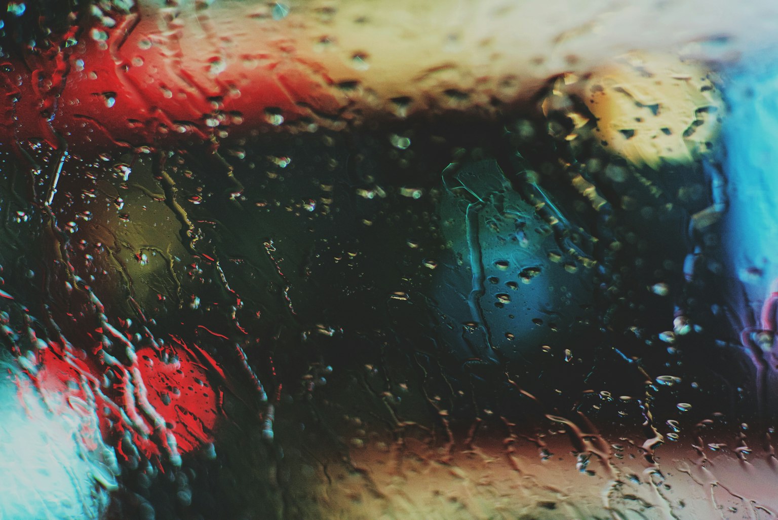 Blurred colorful lights seen through raindrops on glass