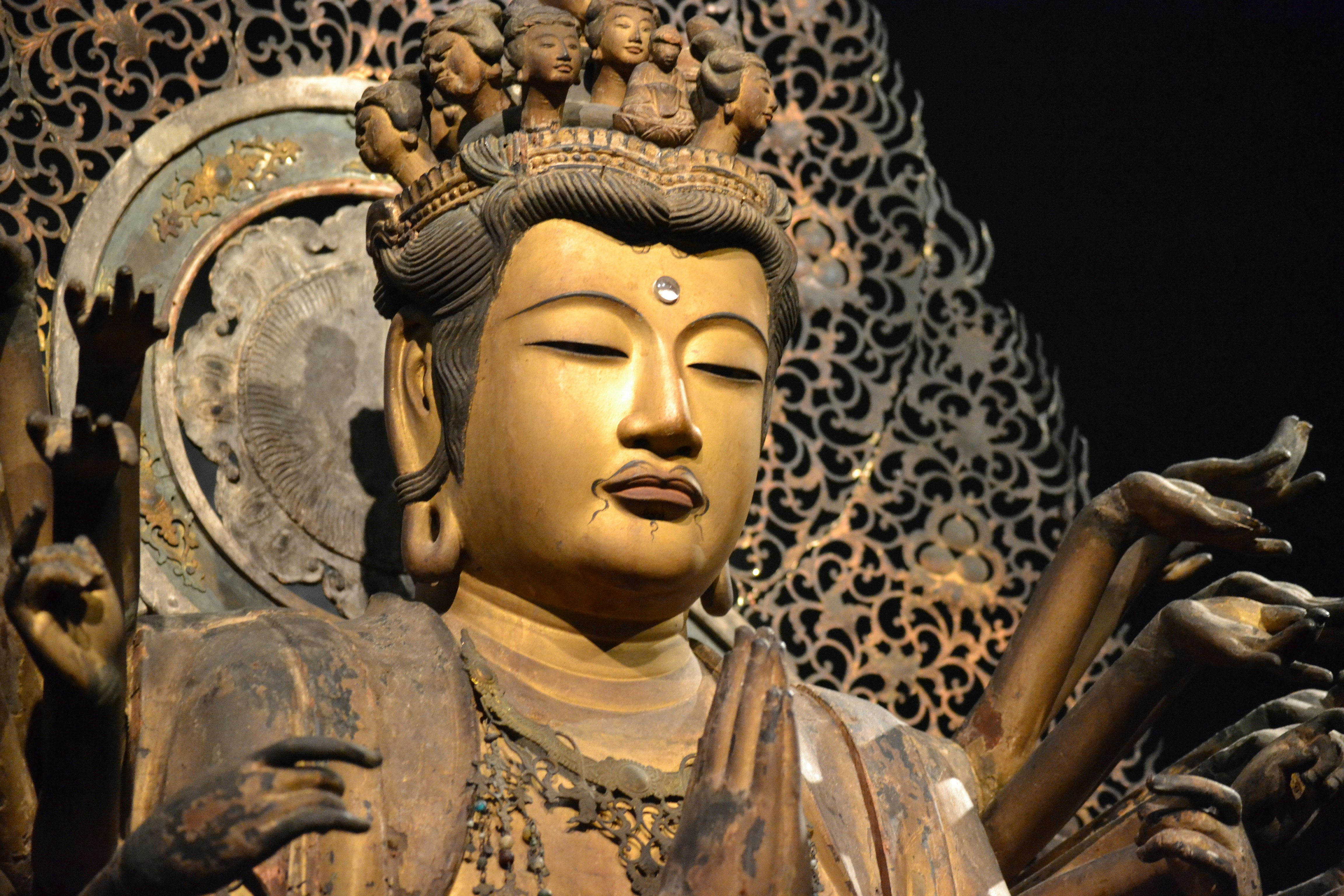金色の仏像の顔と両手が見える装飾的な壁面