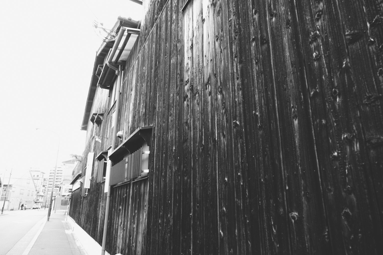 Immagine che mostra un muro di legno nero e parte di un vecchio edificio