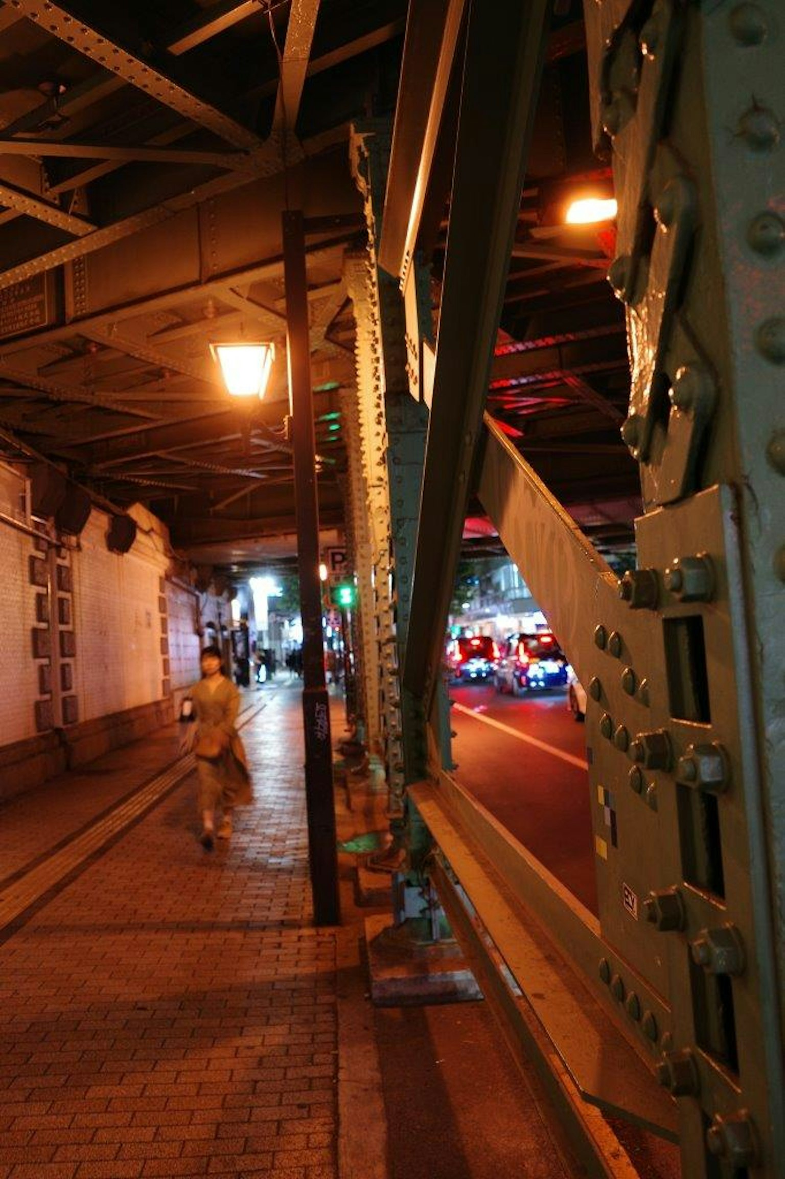 ฉากถนนยามค่ำคืนที่มีโครงสร้างสะพานรถไฟและผู้เดินเท้า