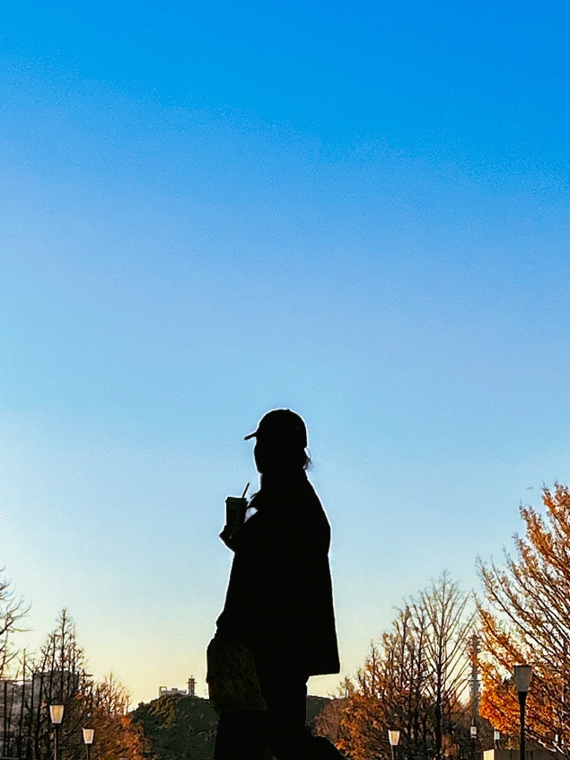 夕暮れの空を背景に立つ人物のシルエット