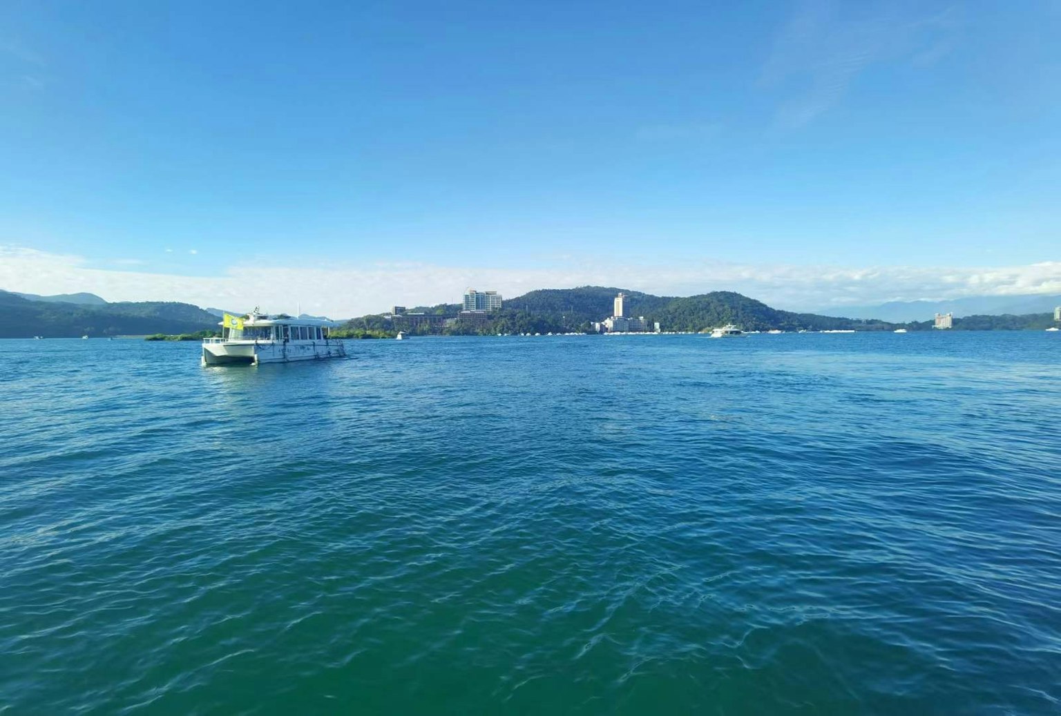 ทิวทัศน์ที่สวยงามของน้ำทะเลสีฟ้าพร้อมเรือและเกาะในระยะไกล