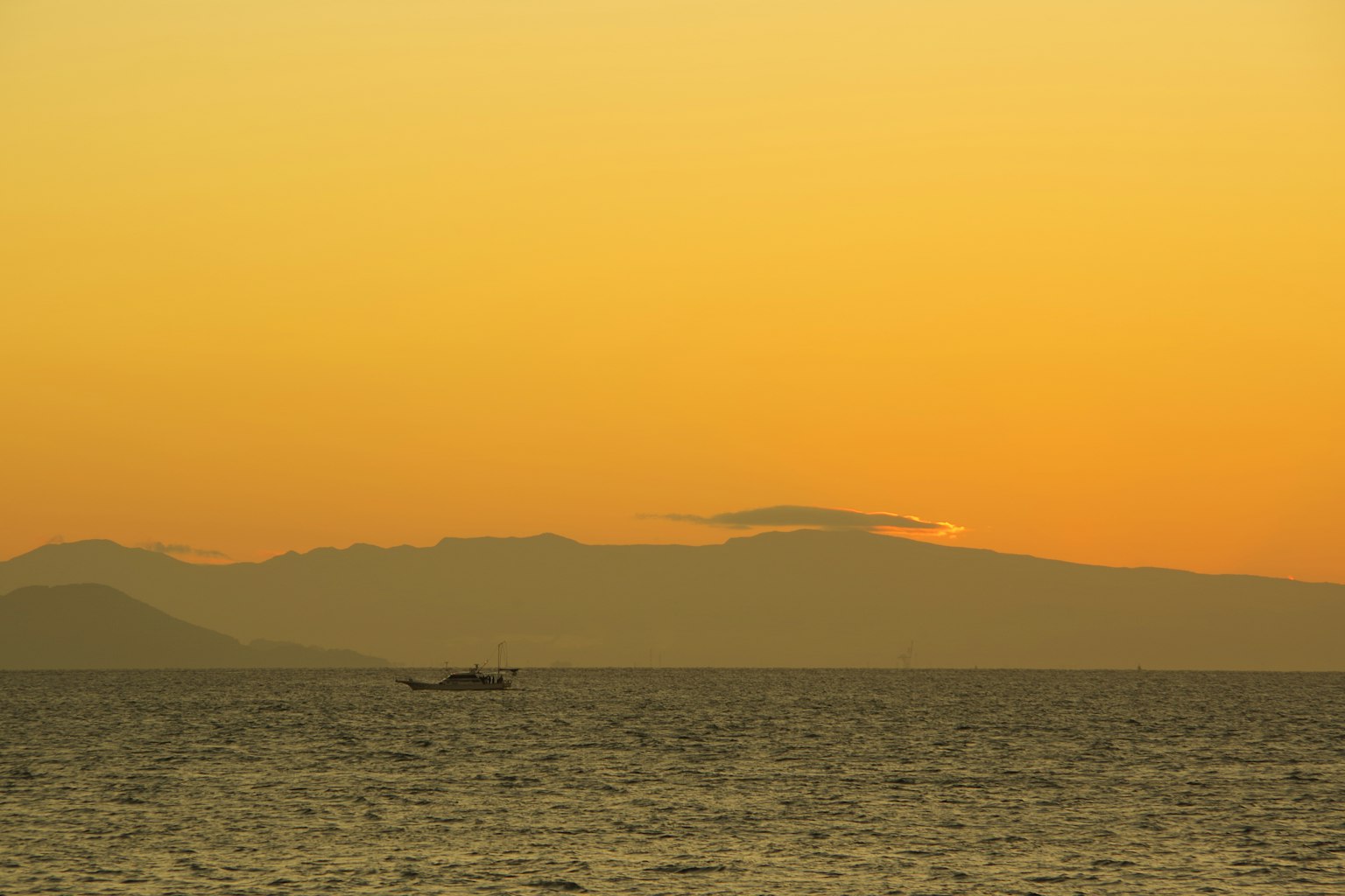 Tramonto sul mare con silhouette di montagne
