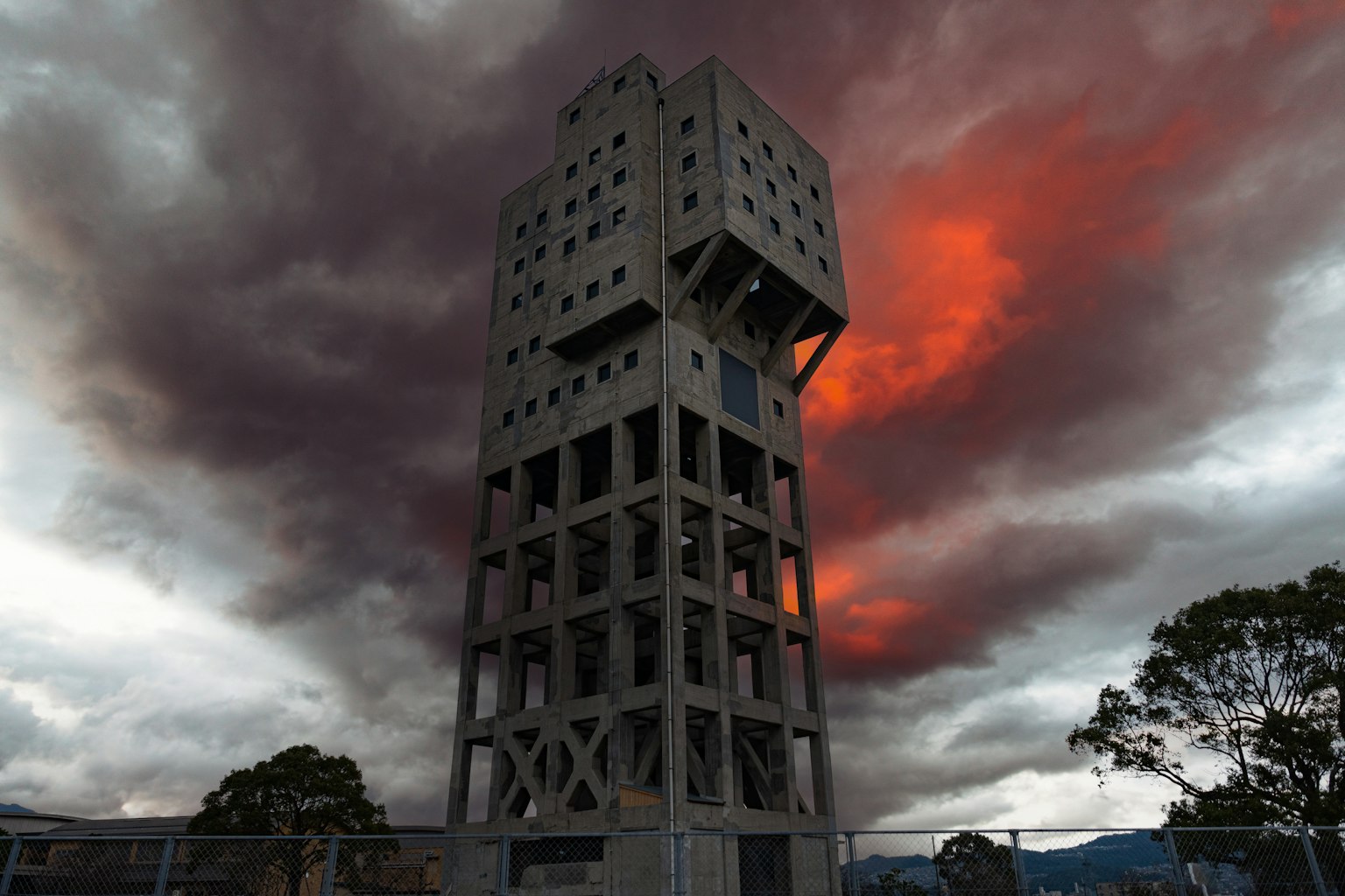 A towering structure against a dramatic sky with dark clouds and red hues