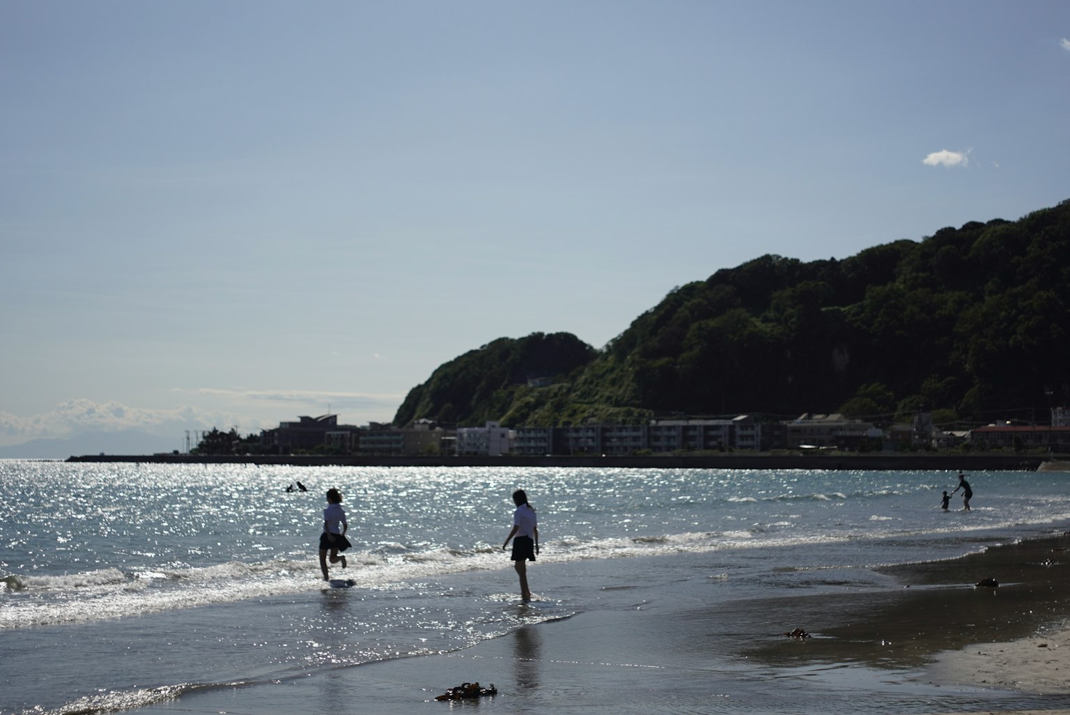 Menschen spielen am Strand mit sanften Wellen