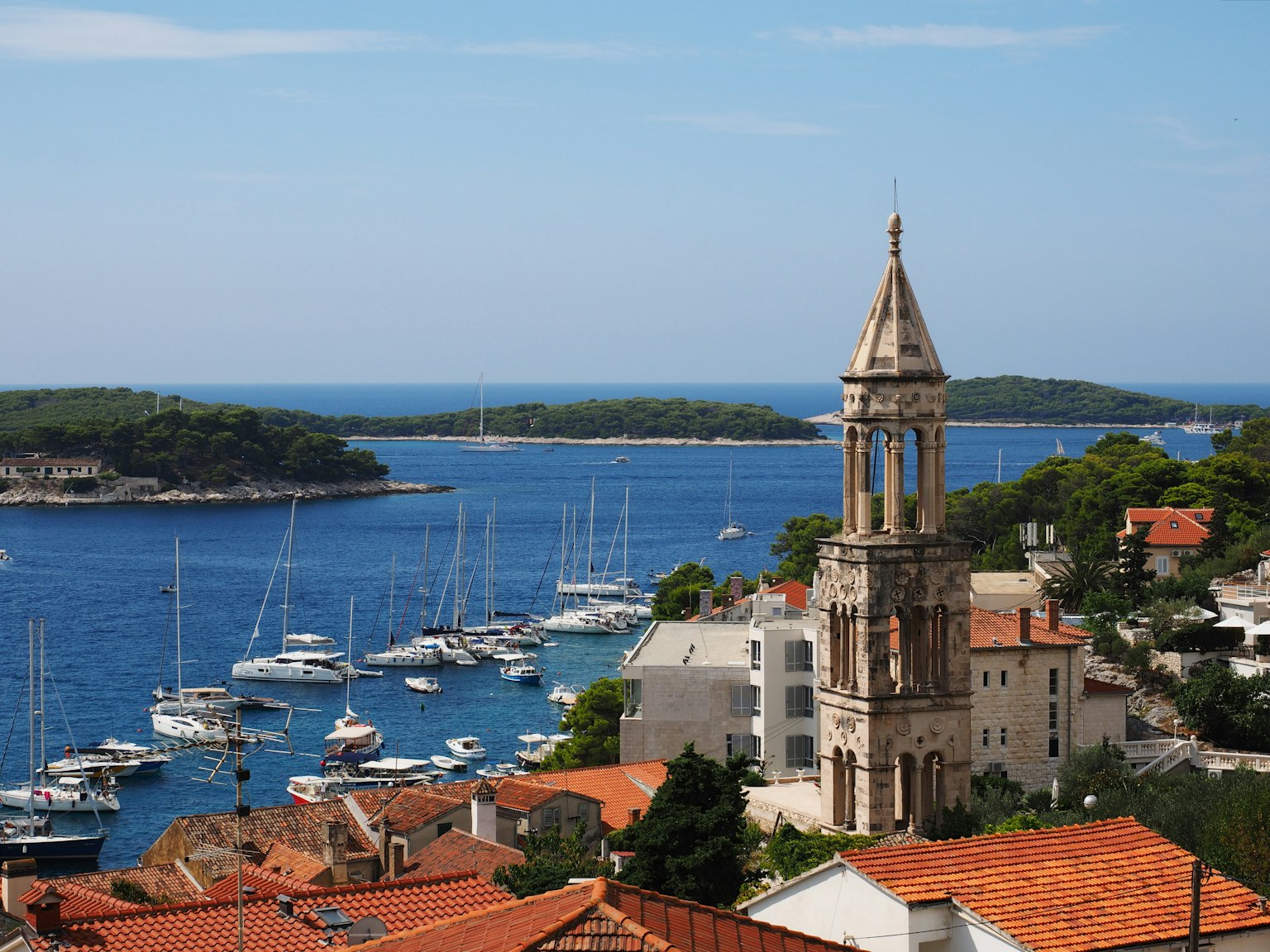Scenic view of a coastal town with a church tower and yachts in the harbor