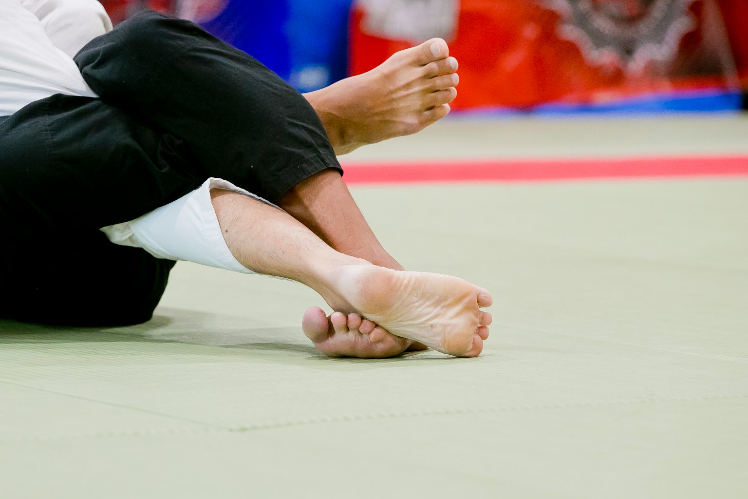 Two judo athletes' feet intertwined on the mat