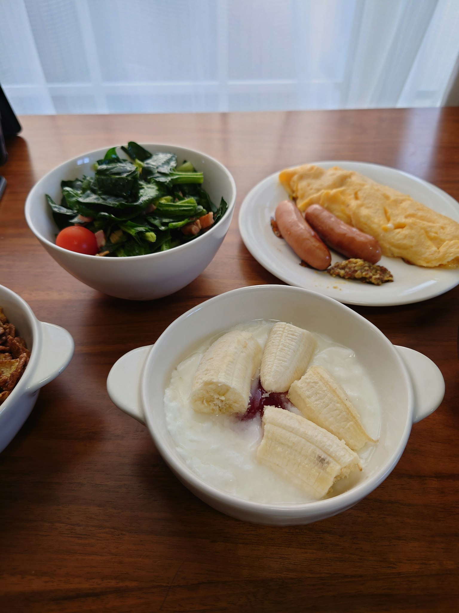 아침 식사 접시에는 샐러드, 스크램블 에그, 소시지 및 바나나 요거트가 있습니다