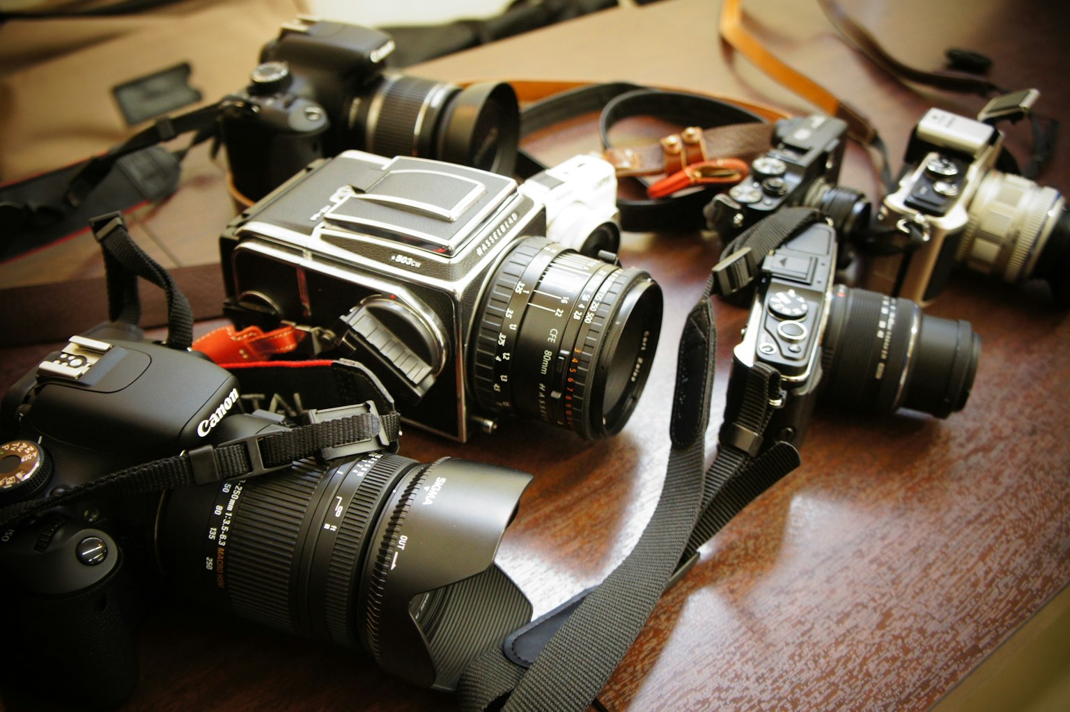 Eine Sammlung von Kameras und Objektiven auf einem Holztisch angeordnet