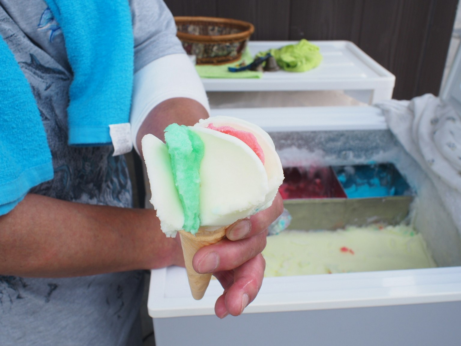 Tangan memegang kerucut es krim dengan bola berwarna di dalam freezer