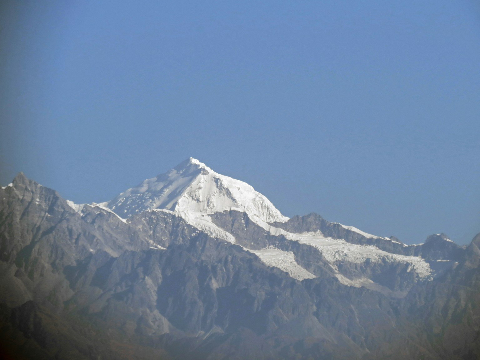 Cima de montaña cubierta de nieve que se eleva bajo un cielo azul claro