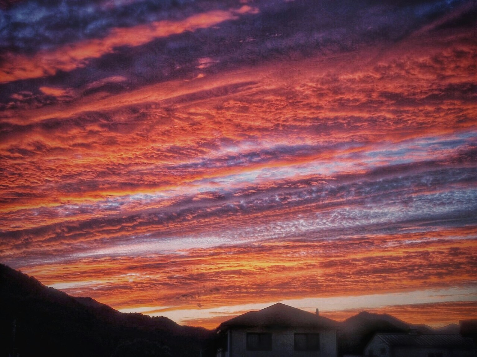 Vibrant sunset sky with colorful clouds and silhouettes of houses