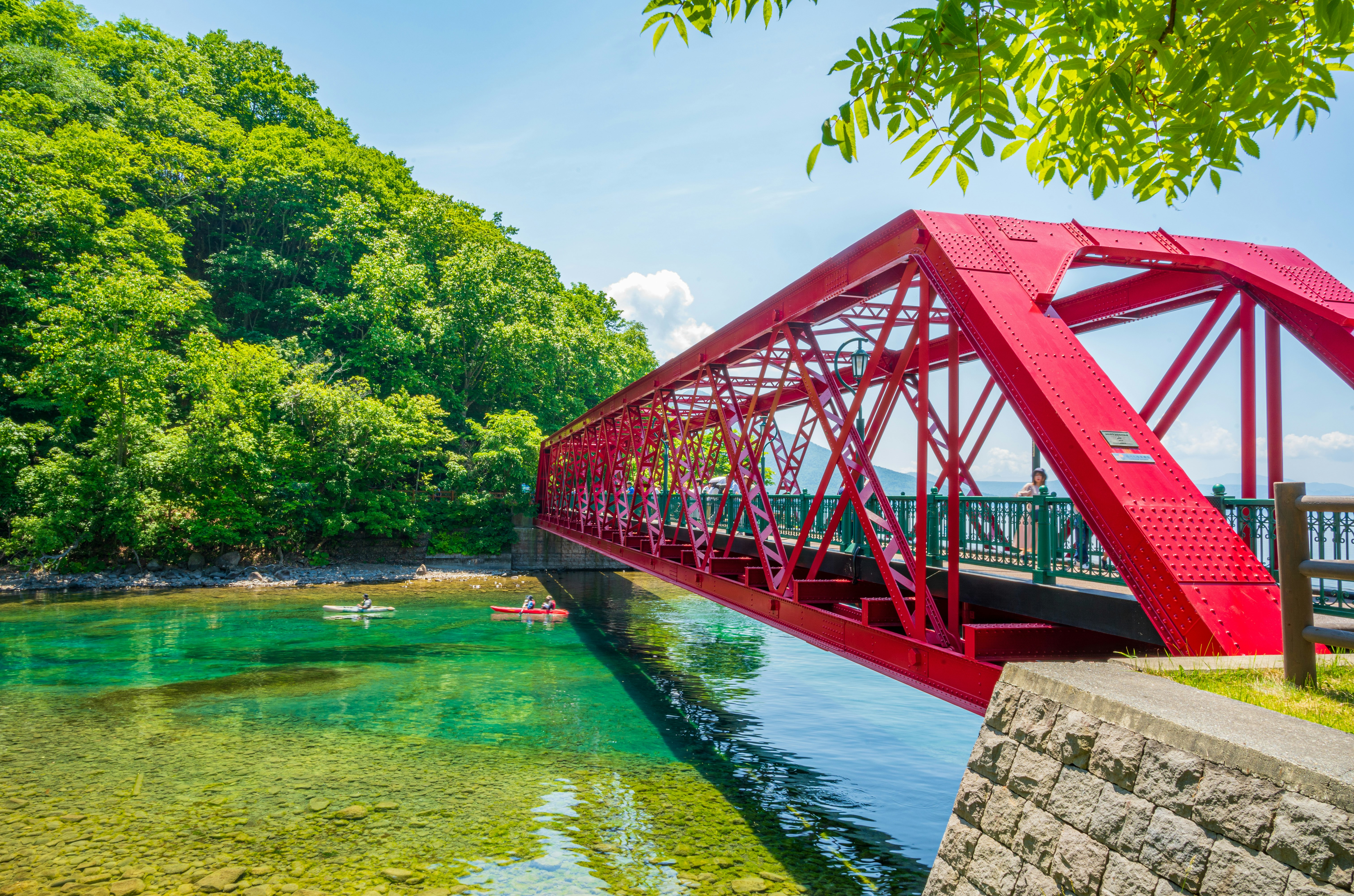 赤いトラス橋とエメラルド色の川の流れ