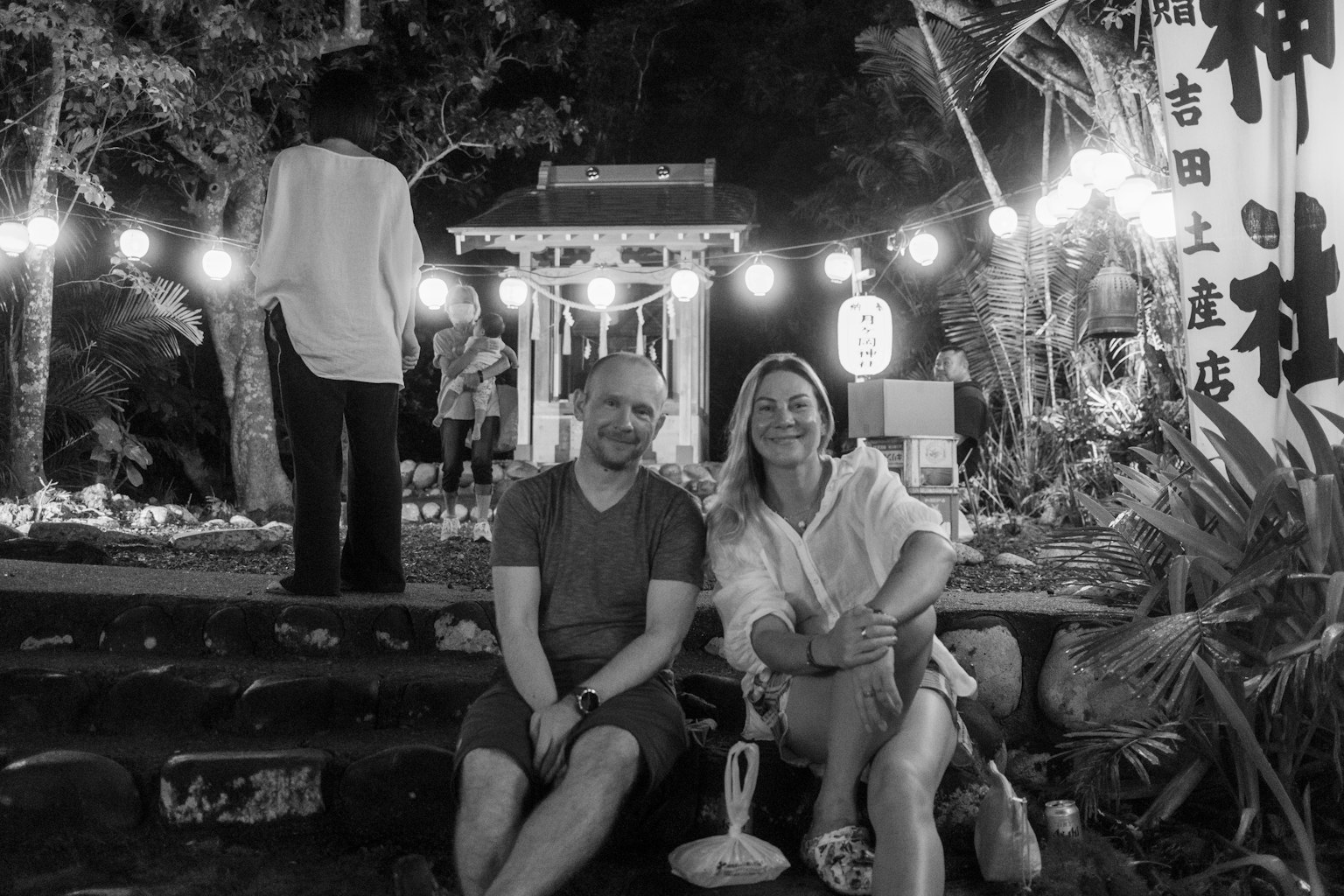 夜の屋外で座っているカップルの写真 照明が周囲を照らし出している