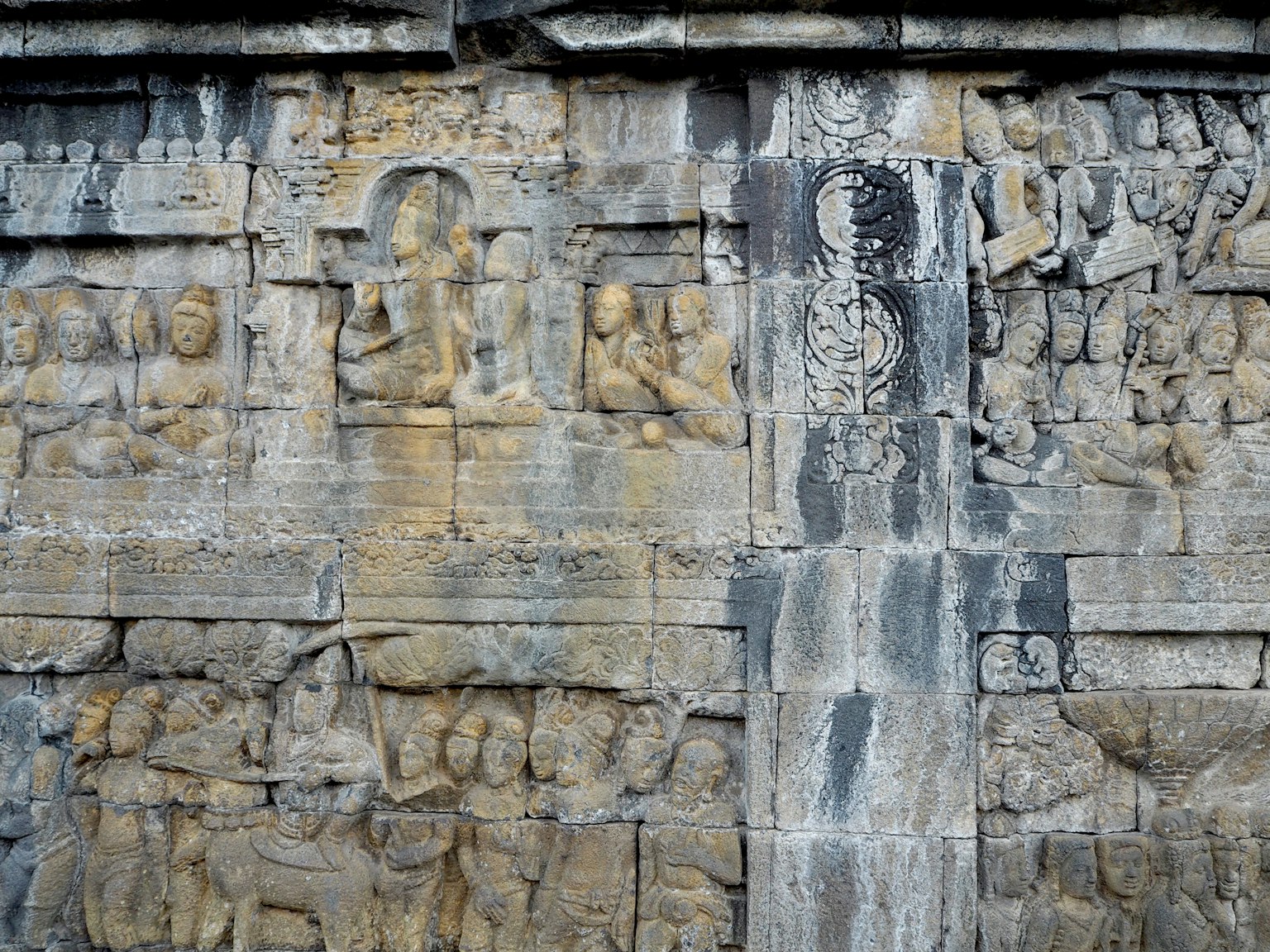 Antike Schnitzereien und Buddha-Statuen an einer Steinwand