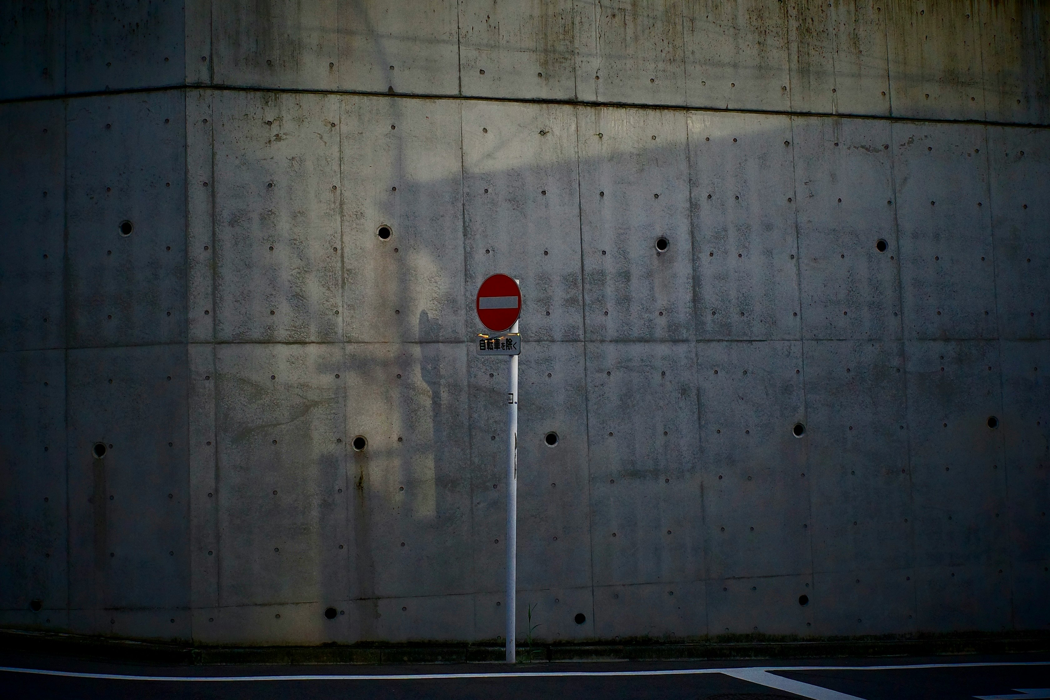 コンクリート壁の前の赤い標識と道路