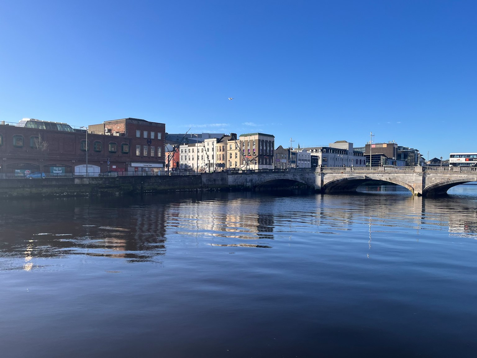 Vue de la ville d'Irlande avec des bâtiments et un pont se reflétant sur la rivière sous un ciel bleu clair