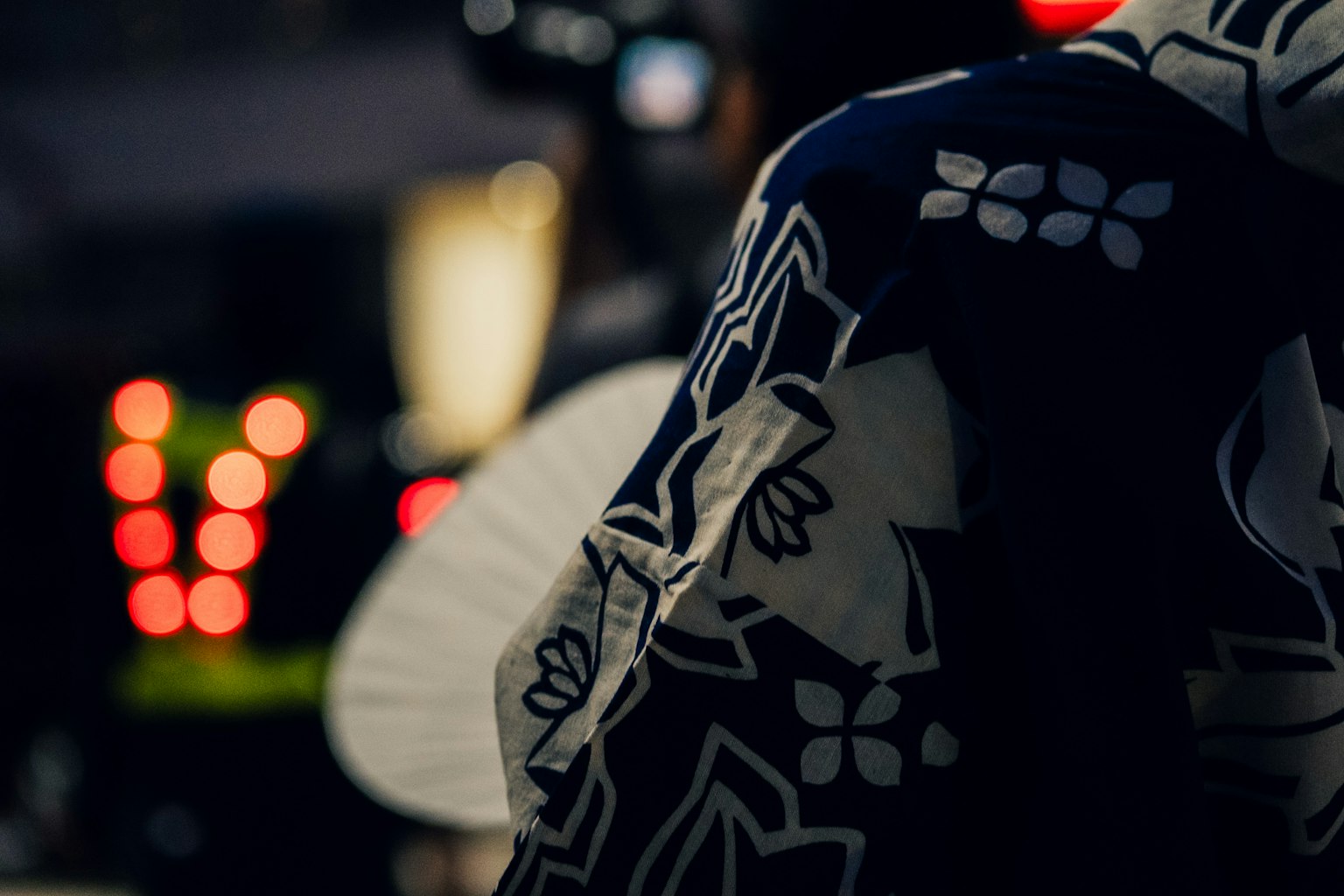 Orang yang mengenakan kimono bermotif di latar belakang gelap