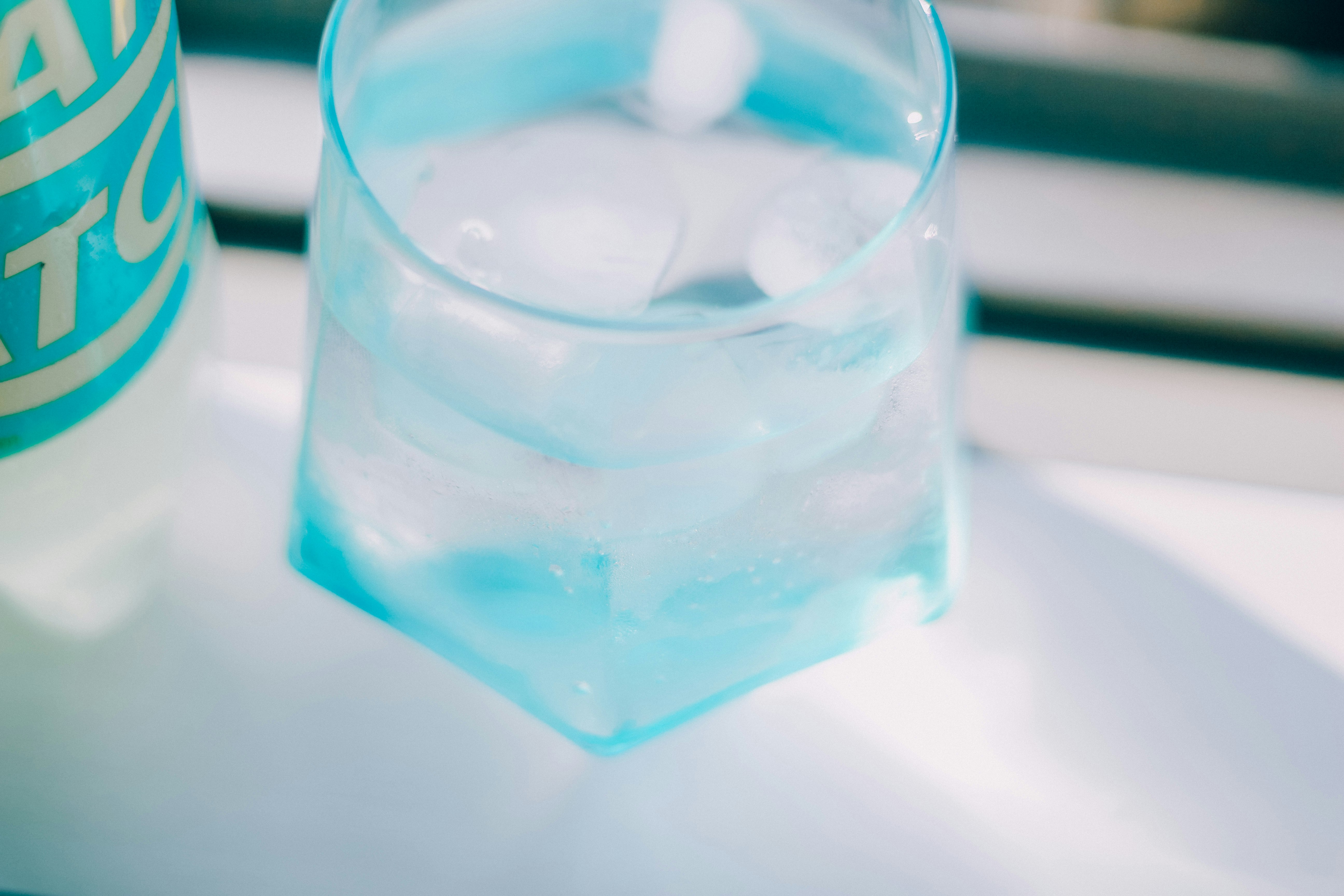 青い水が入った透明なコップと氷のあるテーブル上の静物