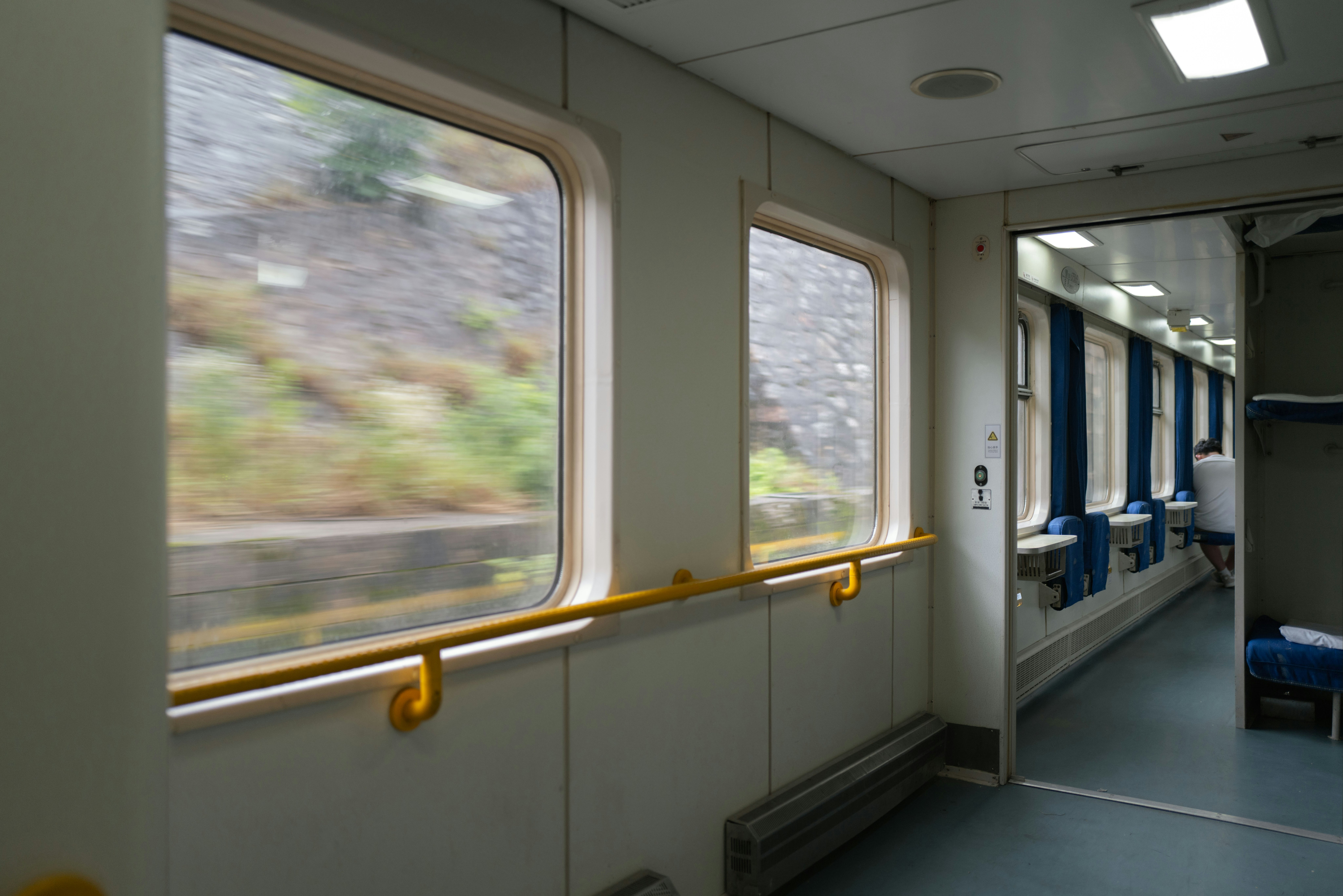 窓のある車内通路を走る列車の風景