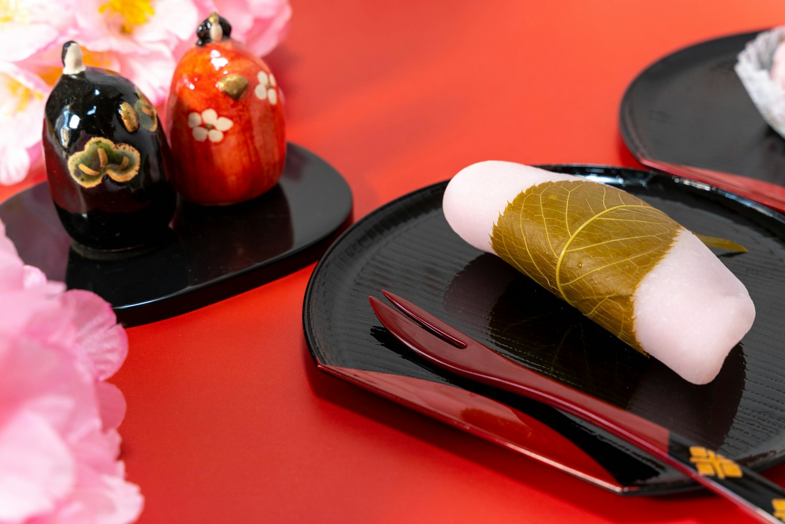 Kue tradisional Jepang di atas piring hitam dengan patung dekoratif