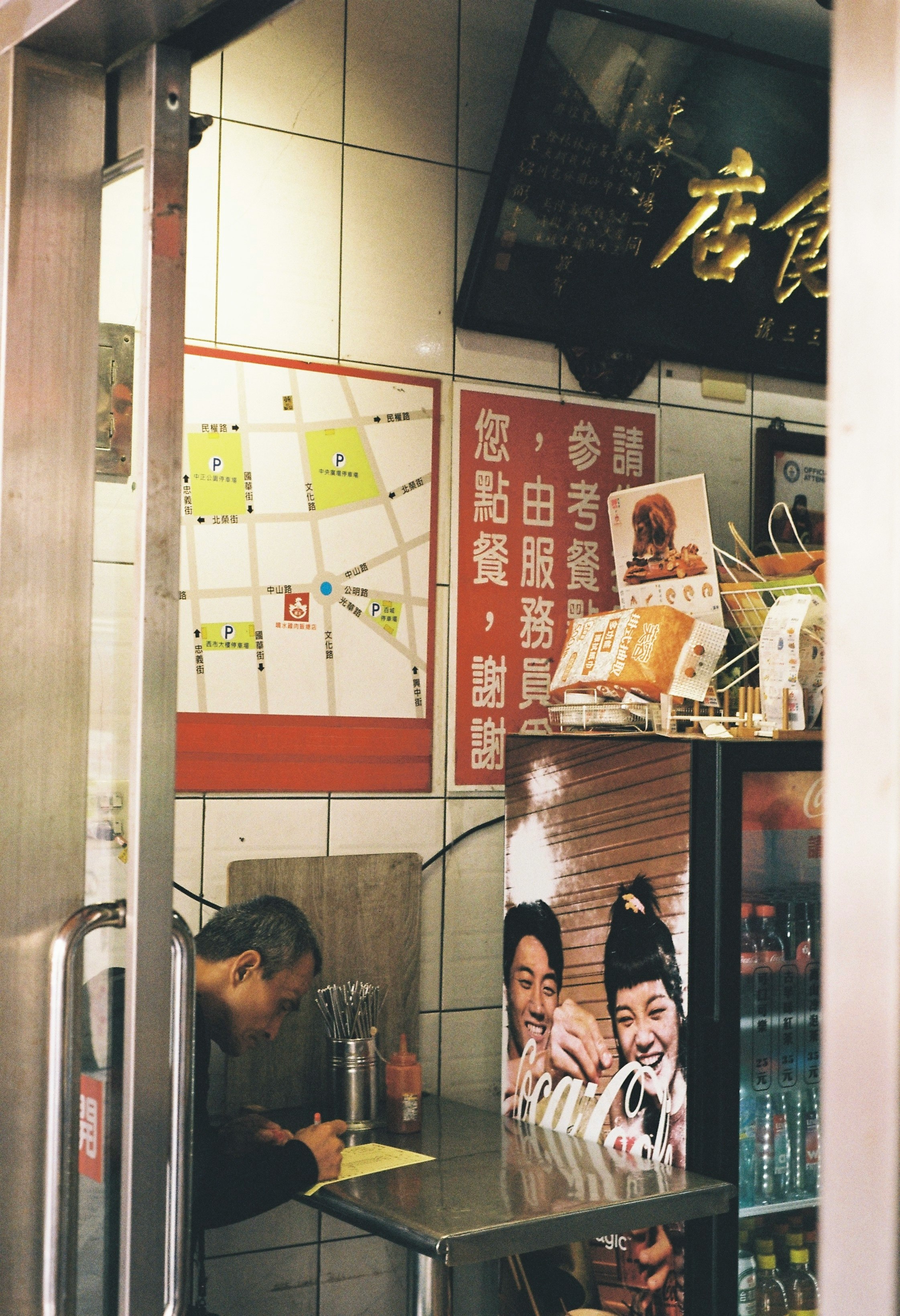 路地の飲食店の店頭で掲示された案内ポスターと看板