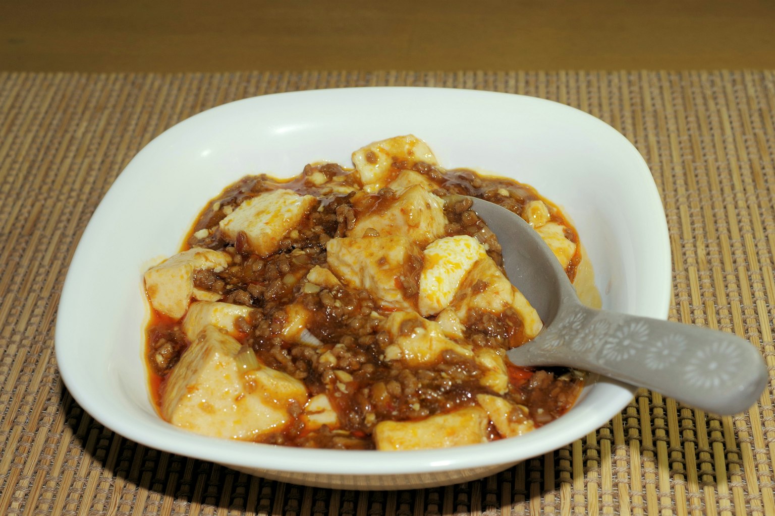 Un plato blanco que presenta tofu y carne picada en una salsa sabrosa