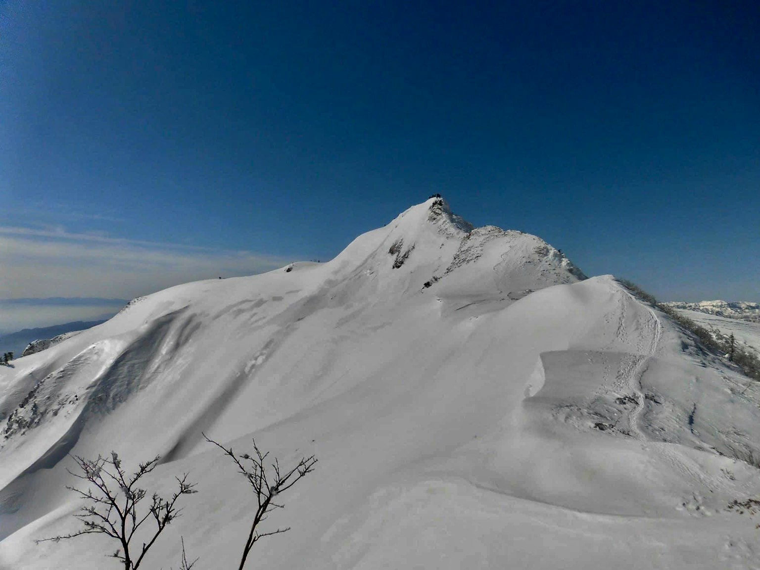 Cima di montagna coperta di neve sotto un cielo blu chiaro