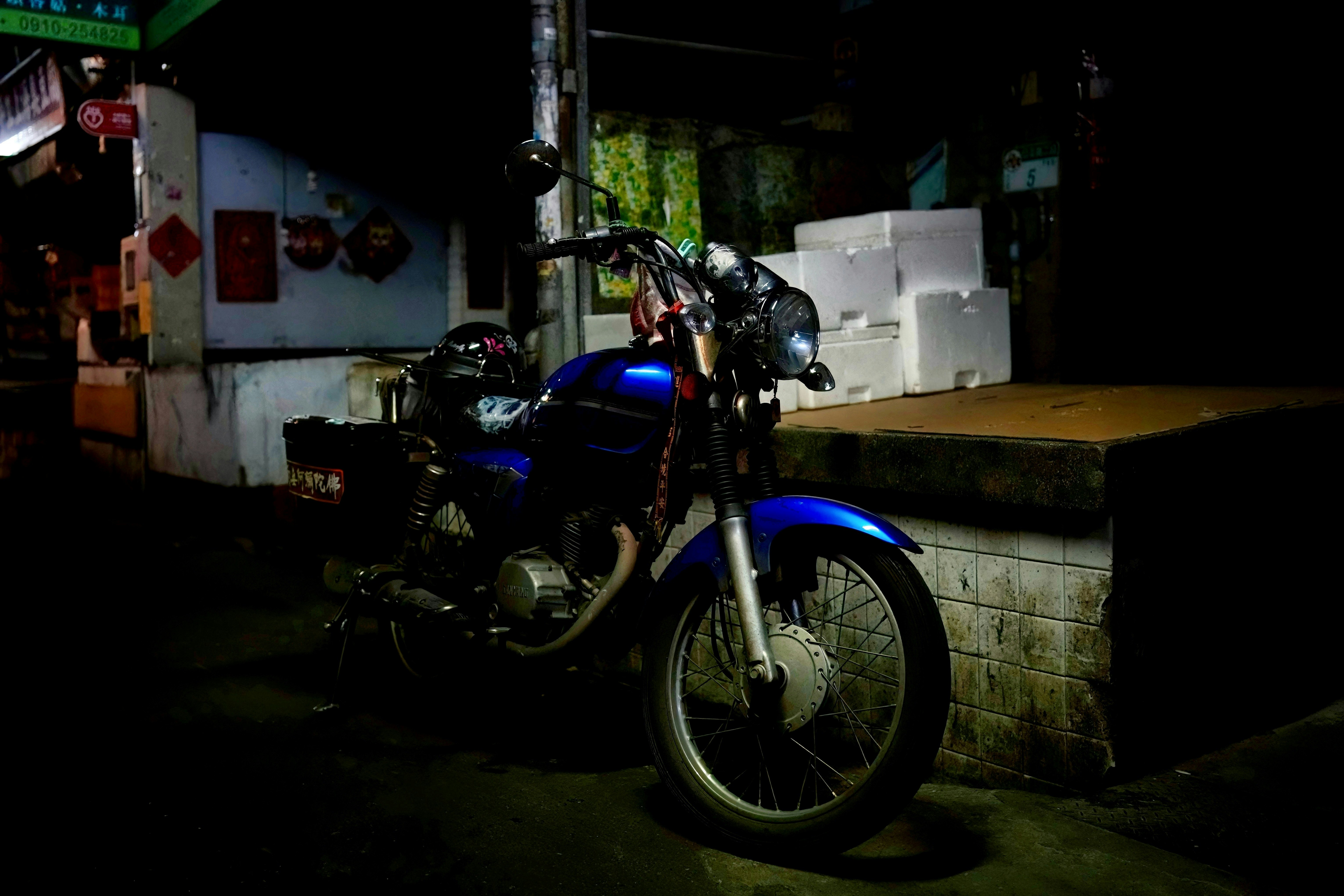 夜の路地に停まるバイクと自転車のある街角