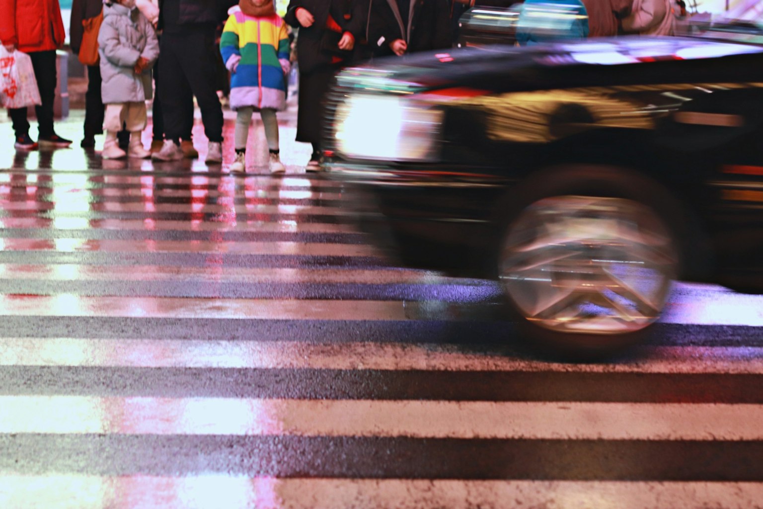 Một chiếc taxi đi qua vạch đi bộ với đám đông người chờ đợi