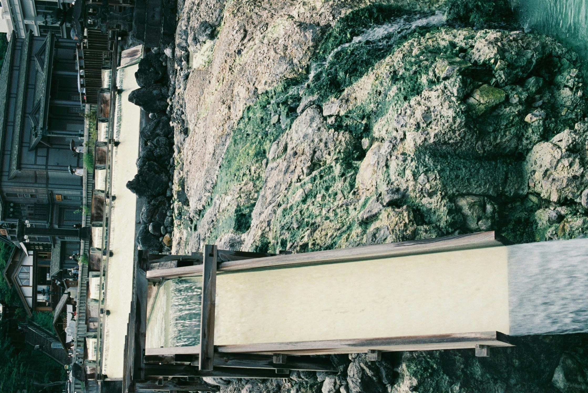 street scene with an elevated bridge and railway beside a rocky cliff