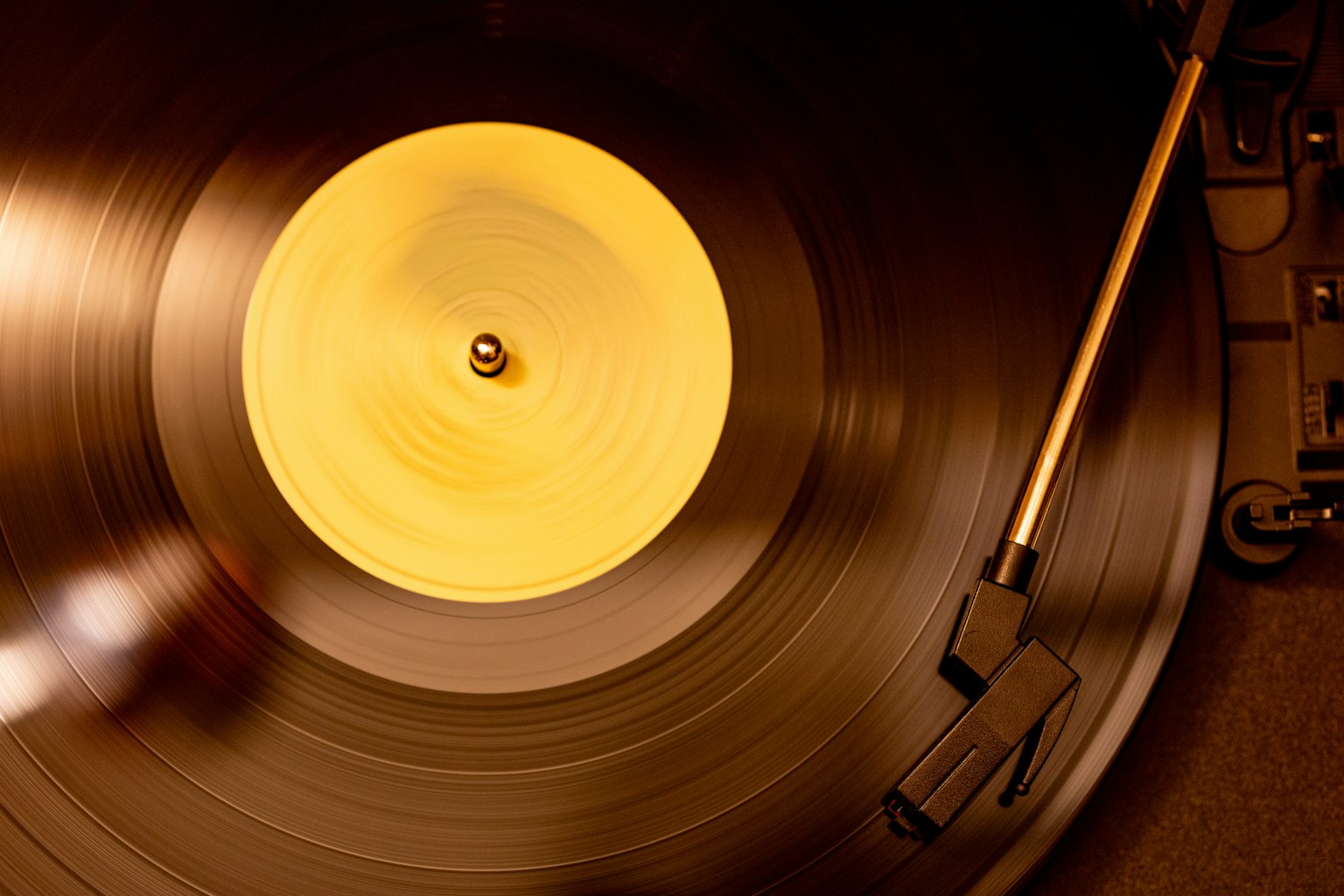 Close-up of a spinning vinyl record on a turntable with a yellow label and tonearm