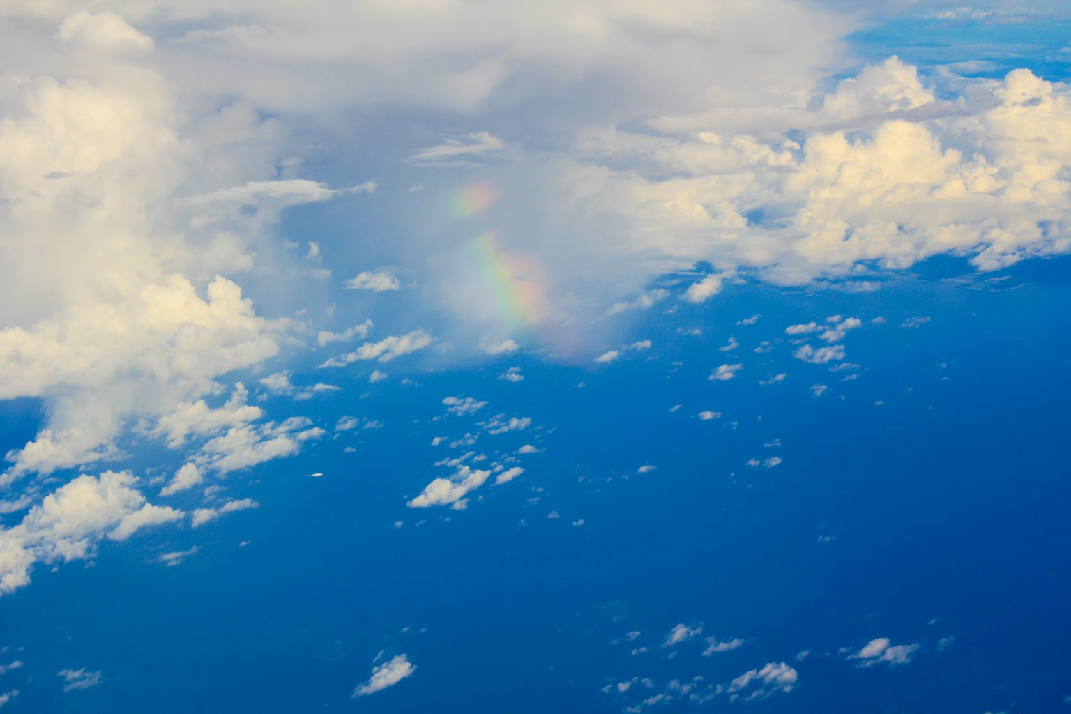 Vue aérienne de l'océan bleu avec des nuages et un arc-en-ciel pâle