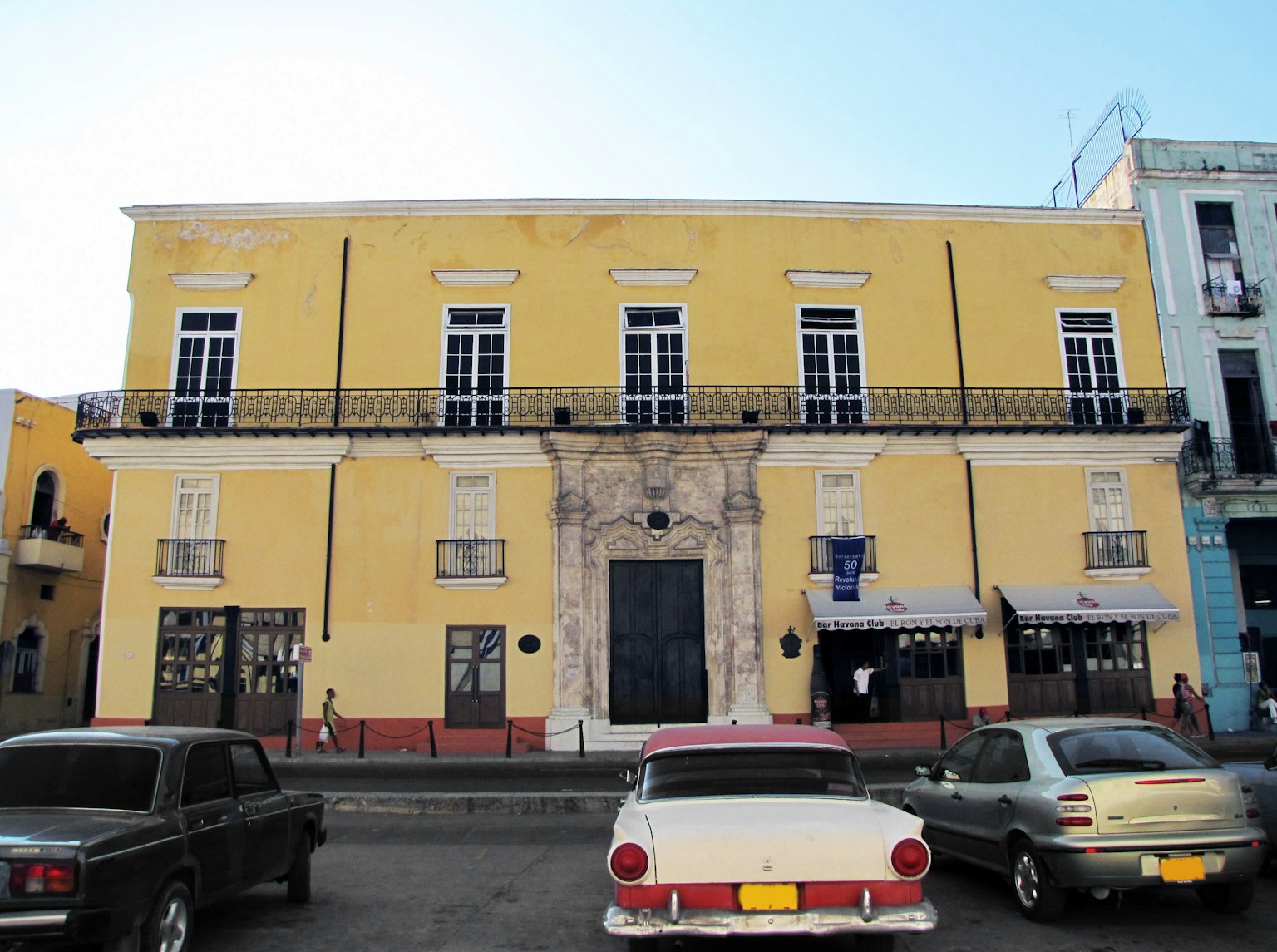 Edificio giallo con auto d'epoca in primo piano