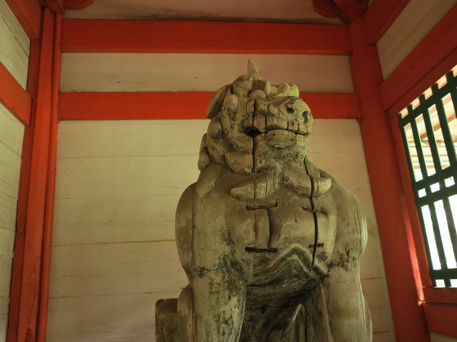 Scultura di leone antico all'interno di un santuario circondata da colonne rosse