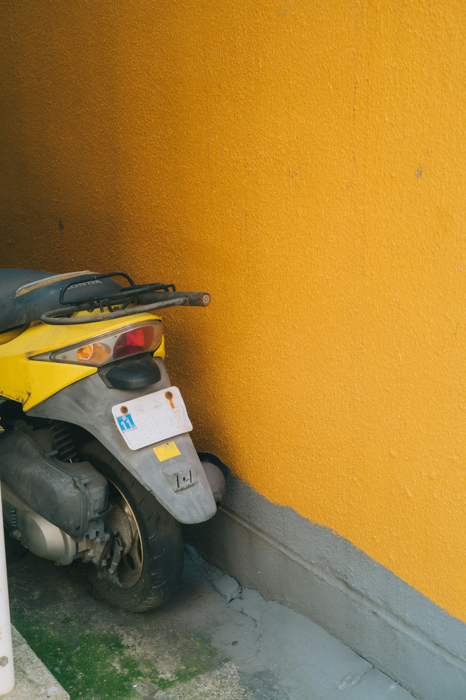 Yellow scooter parked against an orange wall