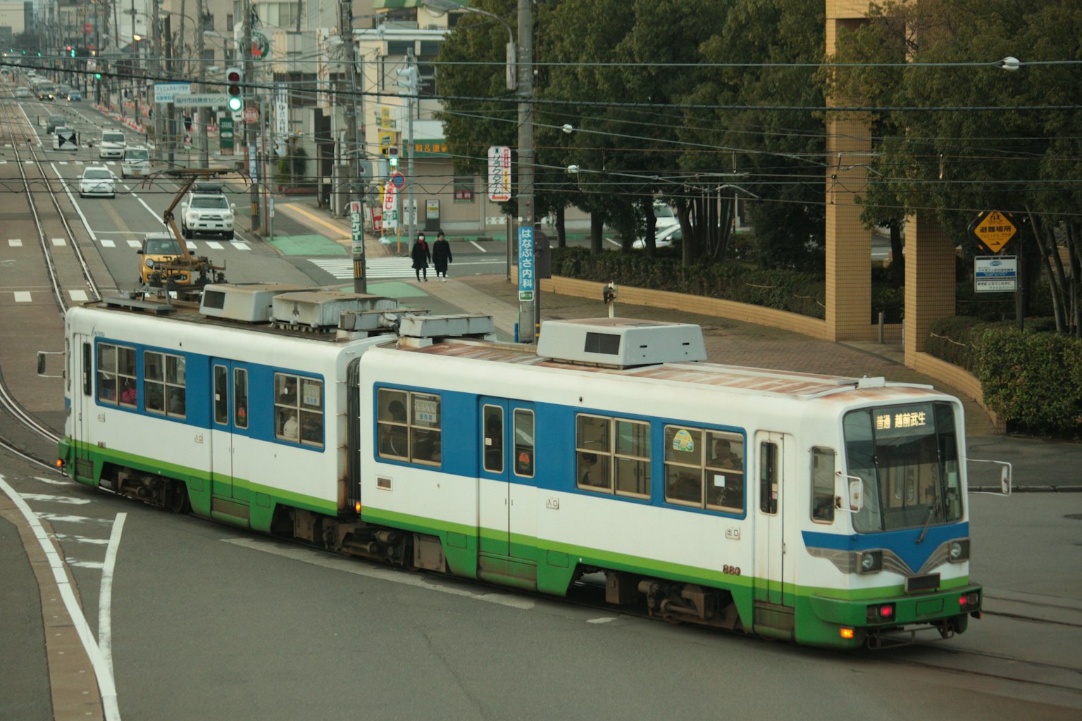 一輛綠色和藍色的電車在城市裡行駛