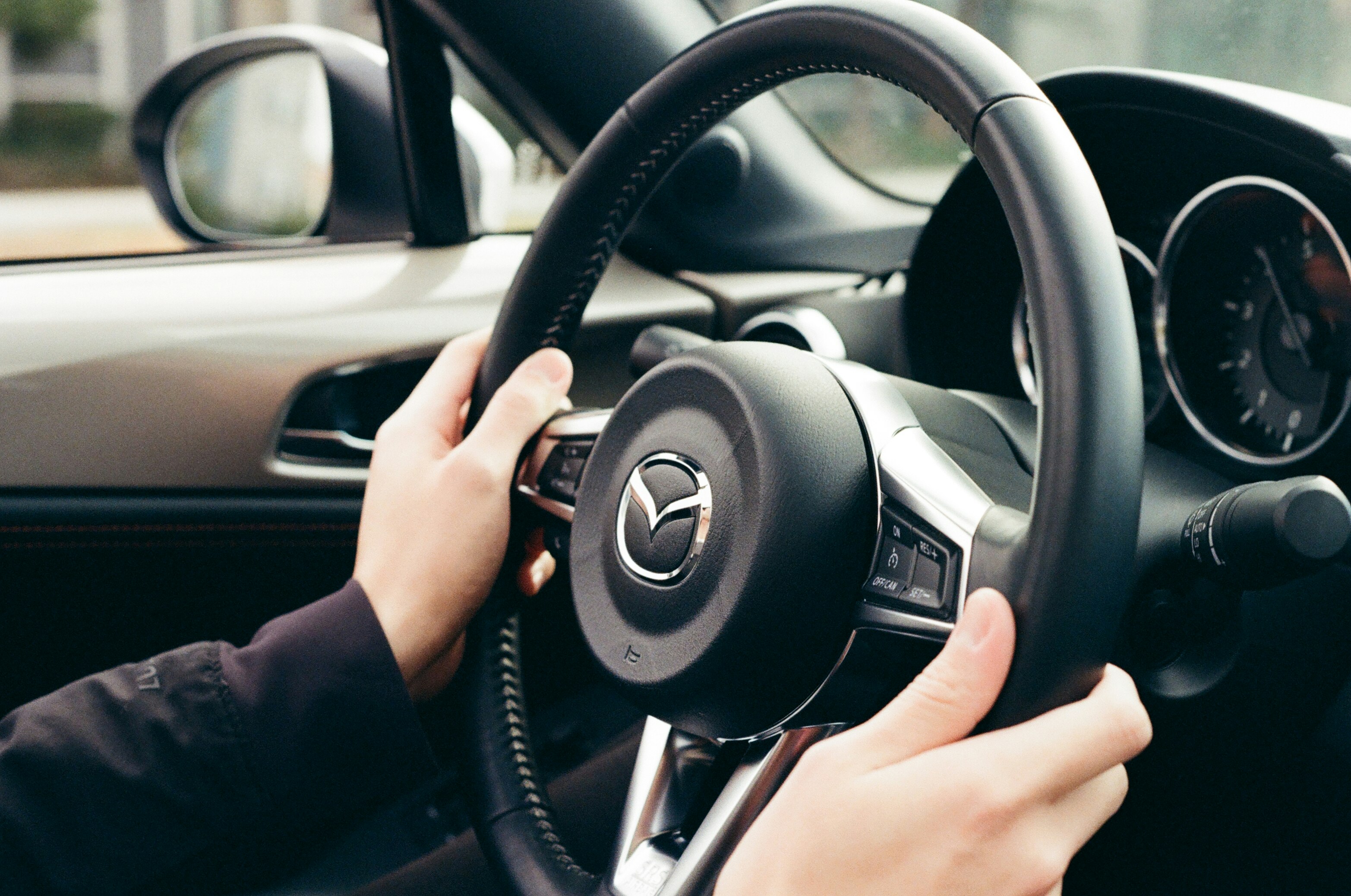 tangan menggenggam setir Mazda MX-5 di dalam mobil