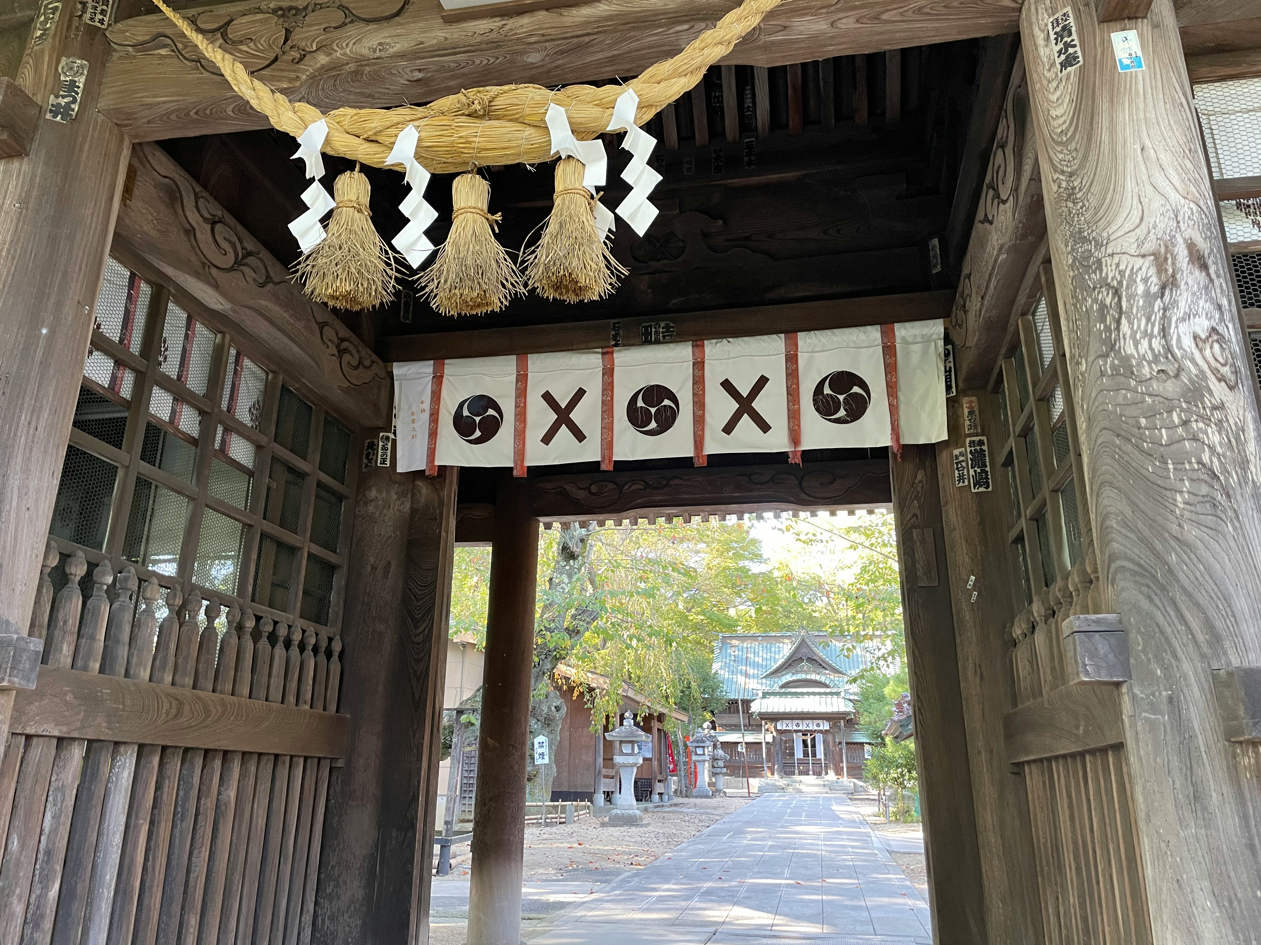 木造の鳥居風の門としめ縄飾りが並ぶ参道の入口